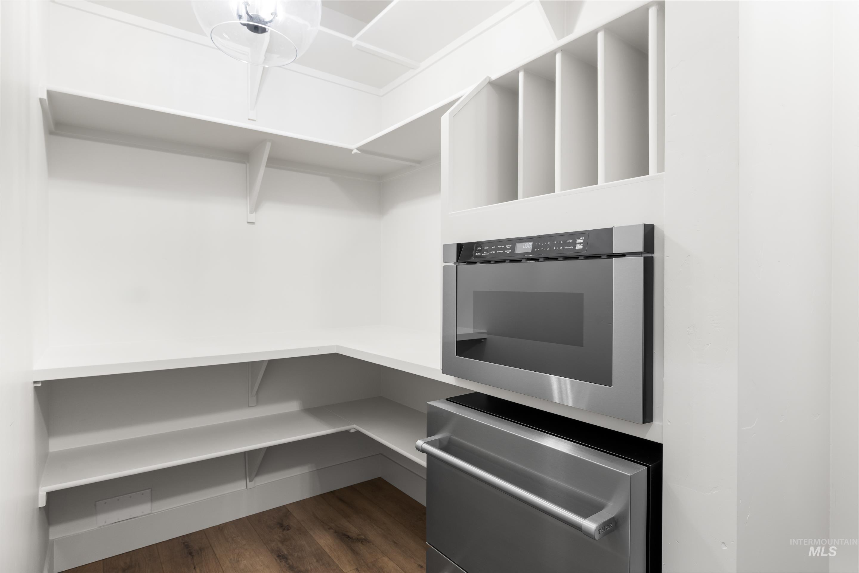 Walk in closet with dark wood-style flooring