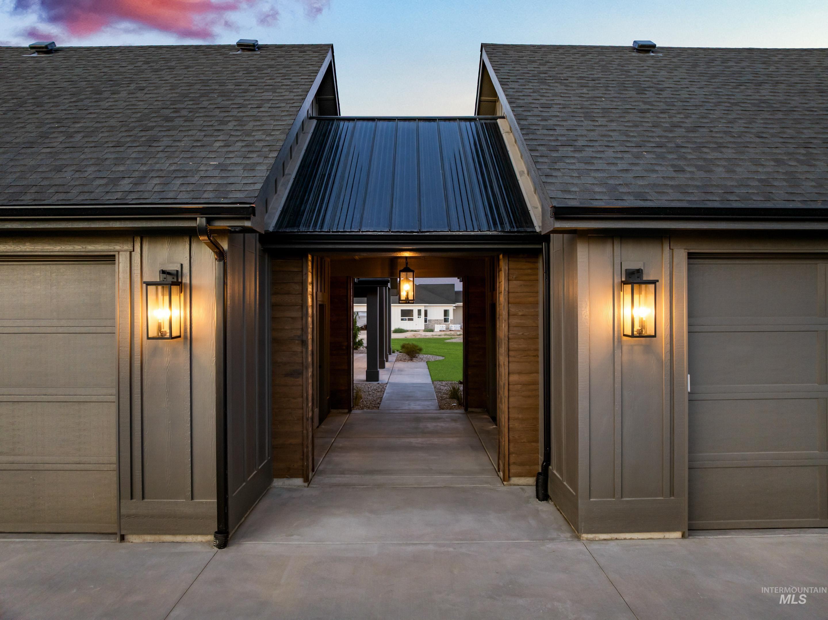 Exterior entry at dusk with an attached garage and roof with shingles
