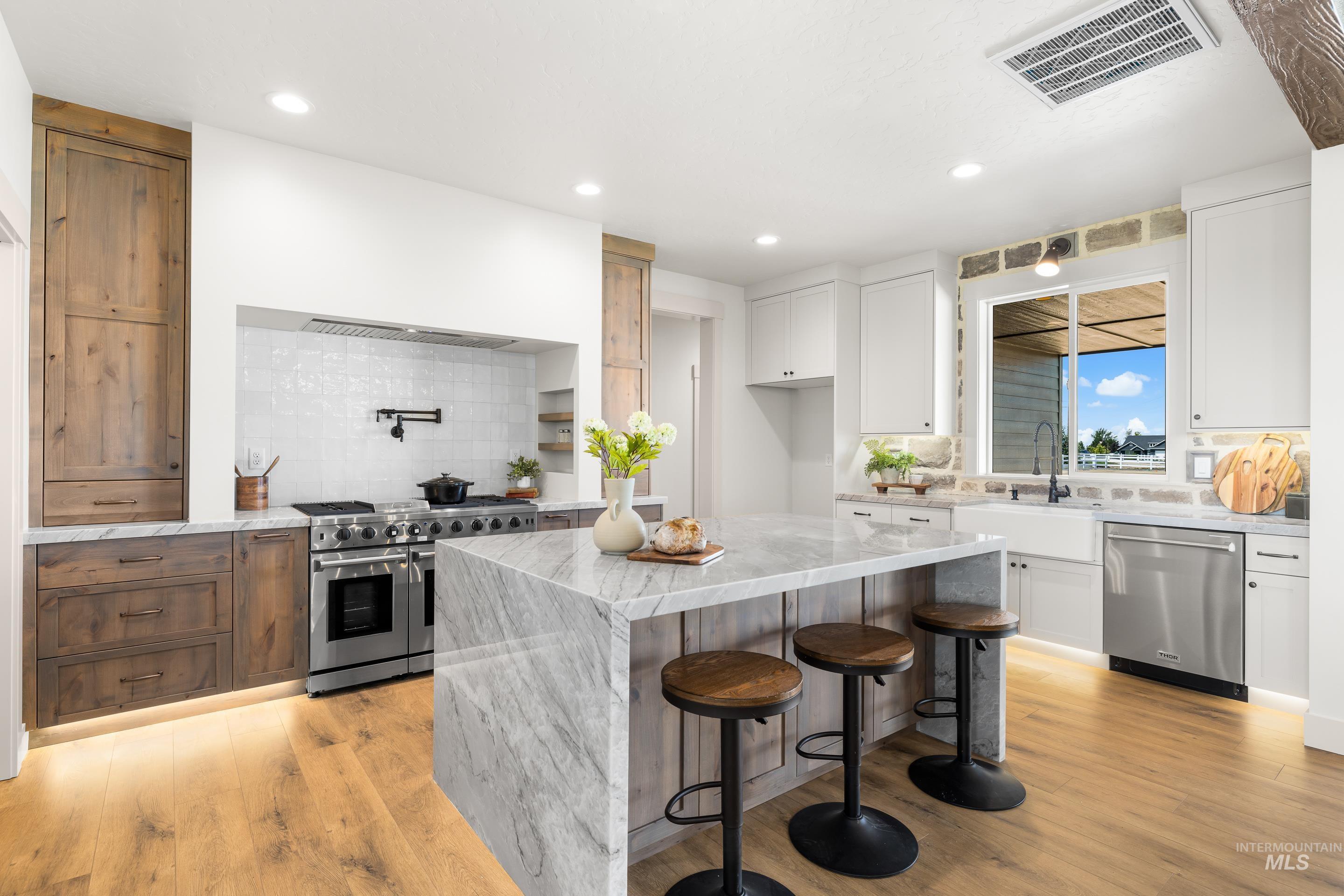 Kitchen featuring tasteful backsplash, stainless steel appliances, a kitchen island, white cabinetry, and recessed lighting