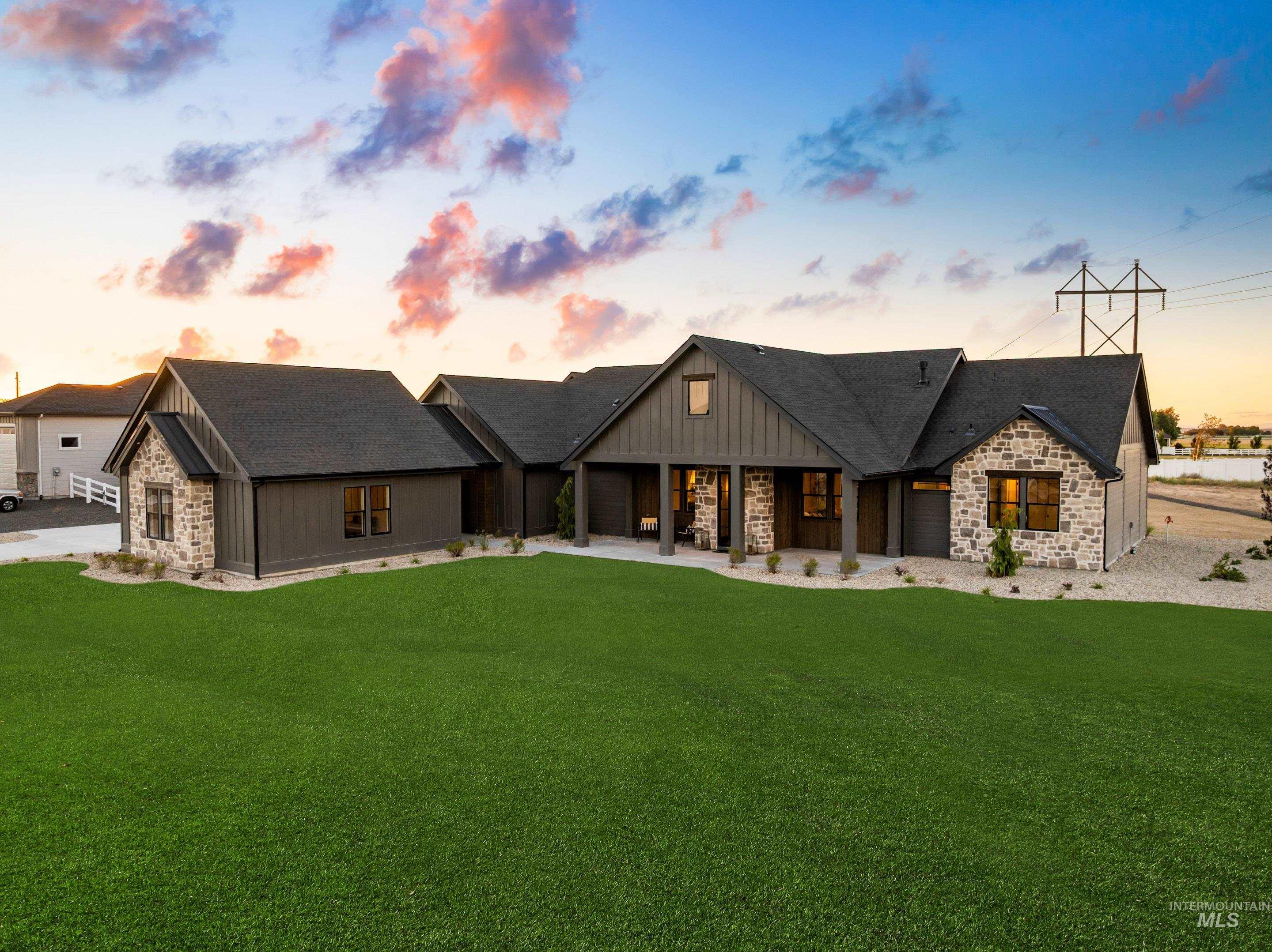 View of front of house with a shingled roof, stone siding, and a front lawn