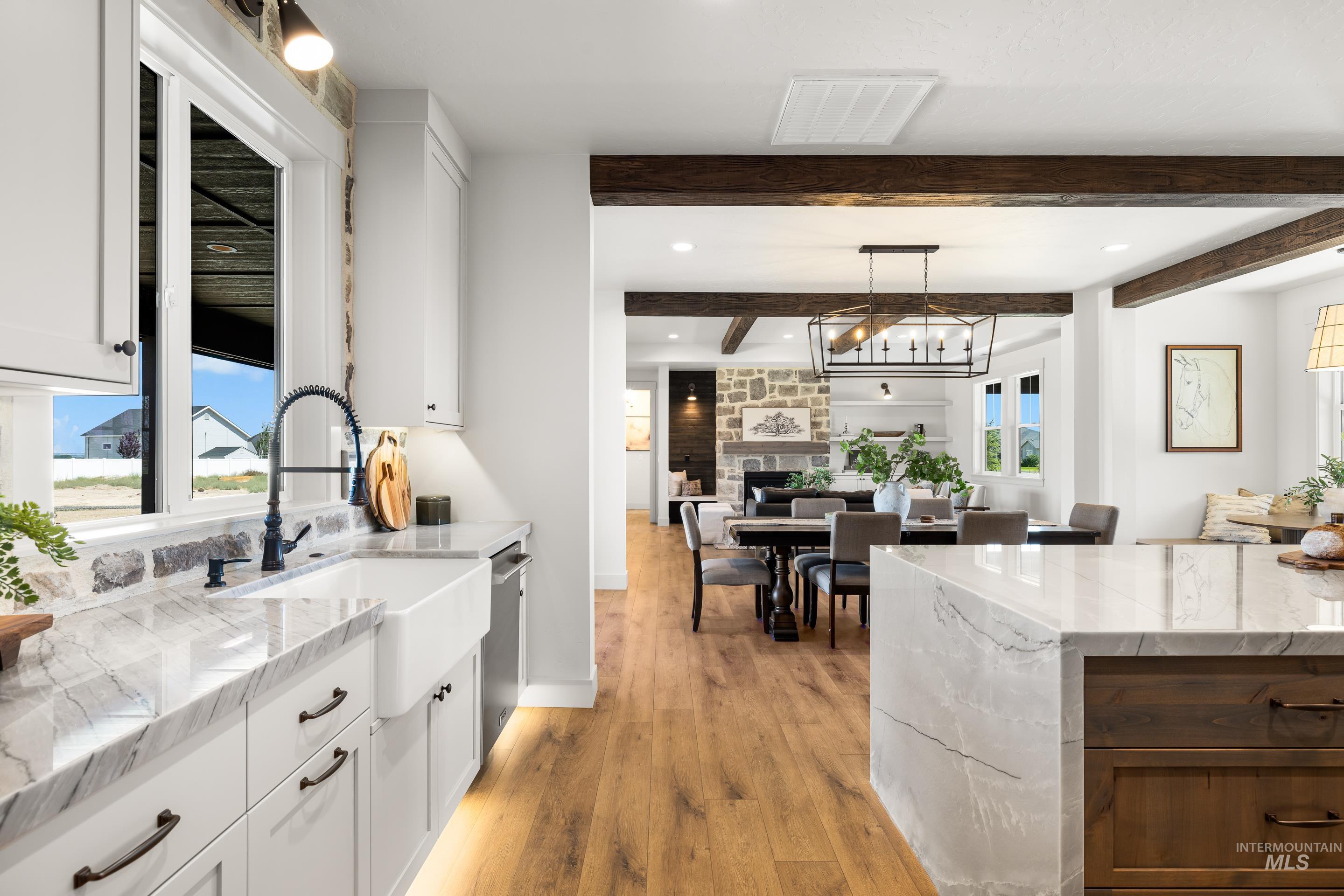 Kitchen featuring light wood-style flooring, beamed ceiling, white cabinetry, light stone counters, and recessed lighting