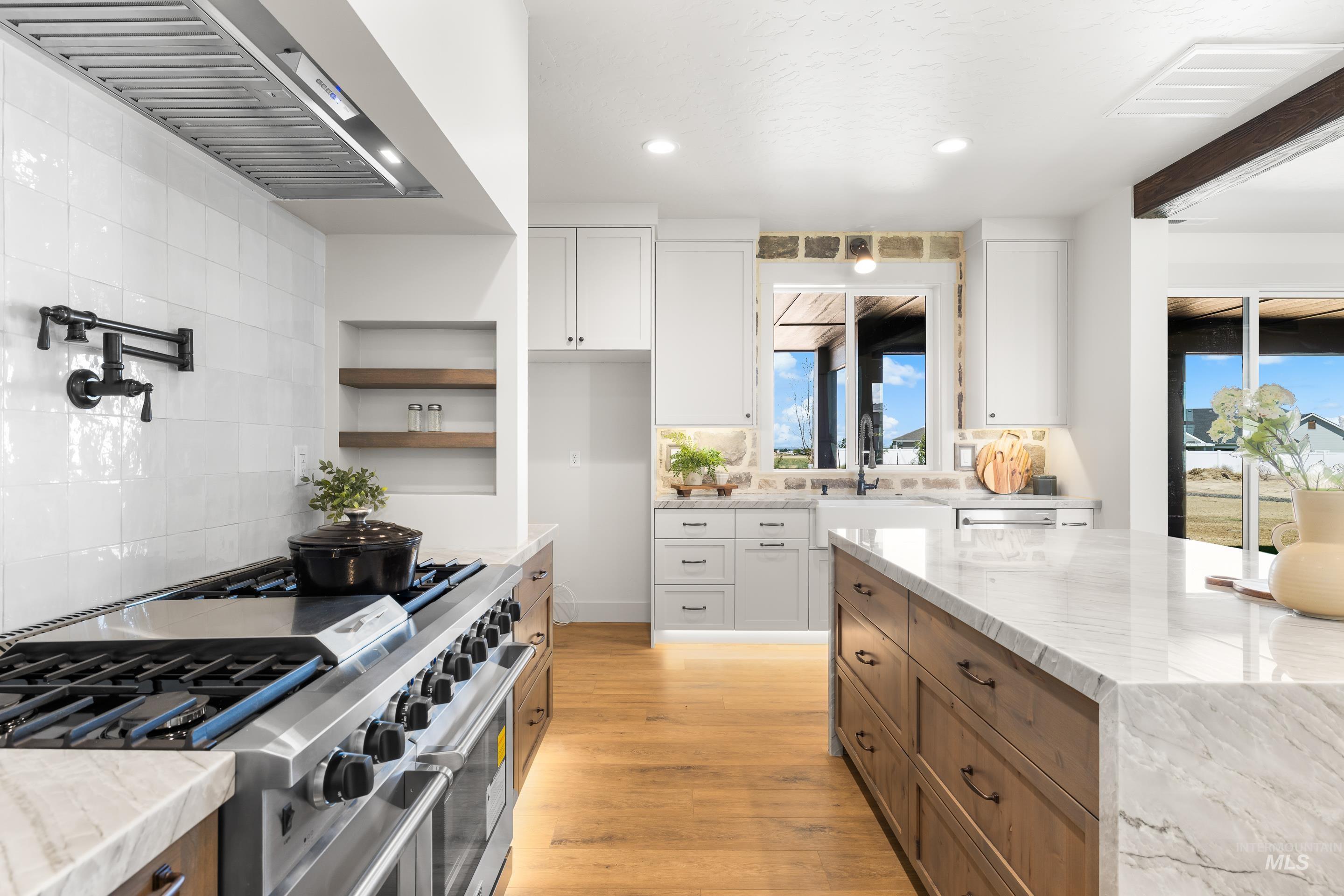 Kitchen featuring range with two ovens, light wood finished floors, white cabinetry, and recessed lighting
