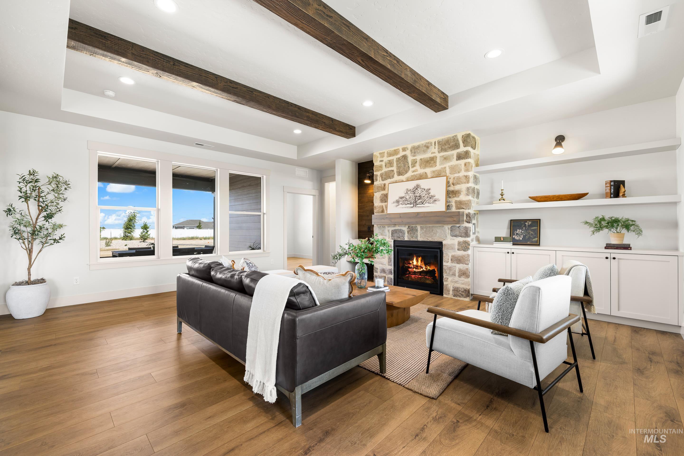 Living room featuring wood finished floors, a stone fireplace, beam ceiling, and recessed lighting