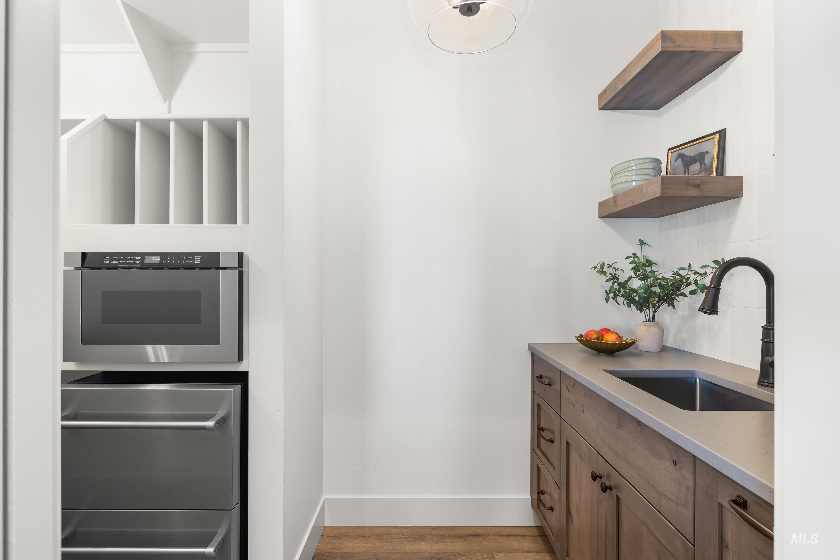 Kitchen featuring wood finished floors, open shelves, and light countertops