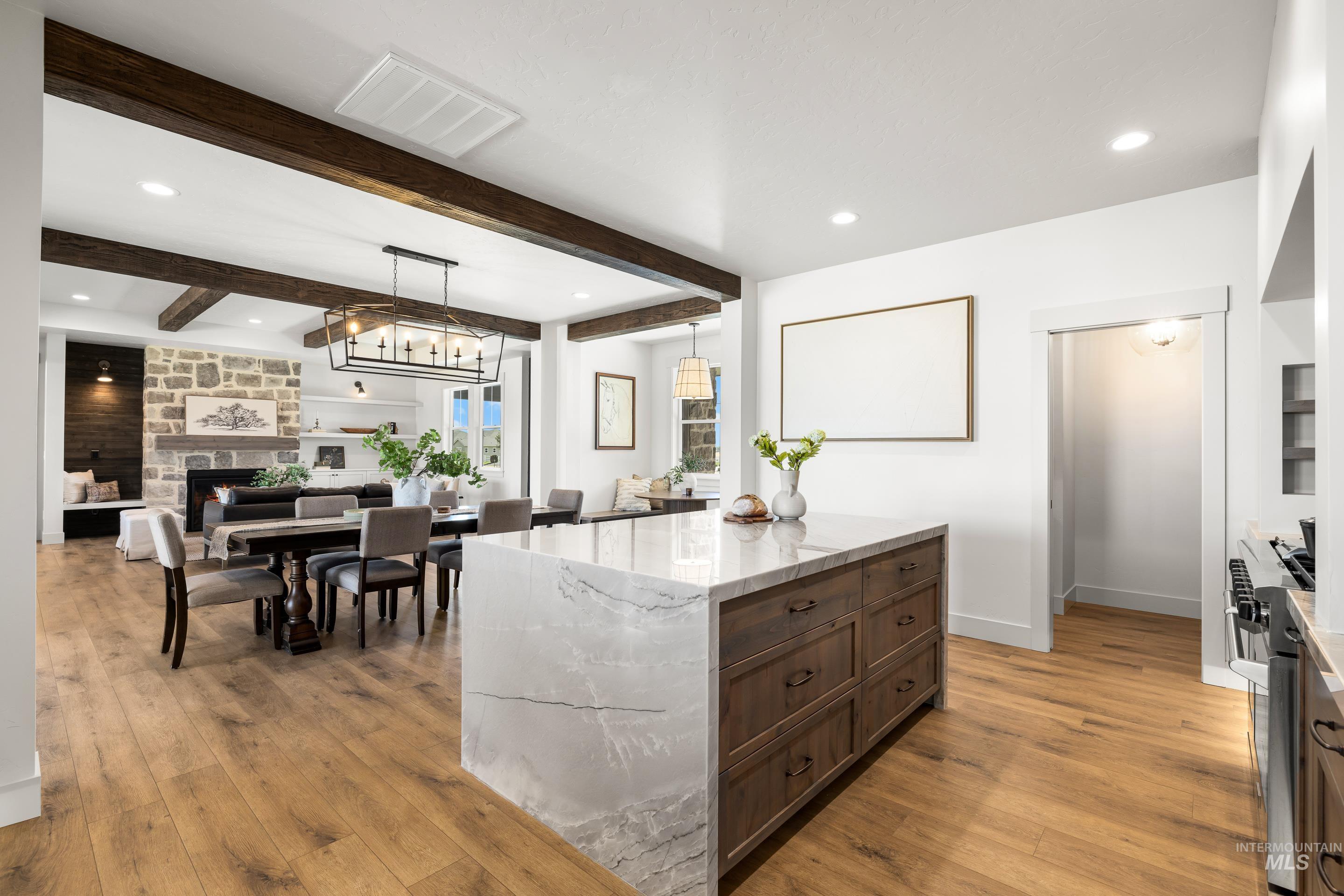 Kitchen with recessed lighting, light wood finished floors, stove, light stone counters, and beam ceiling