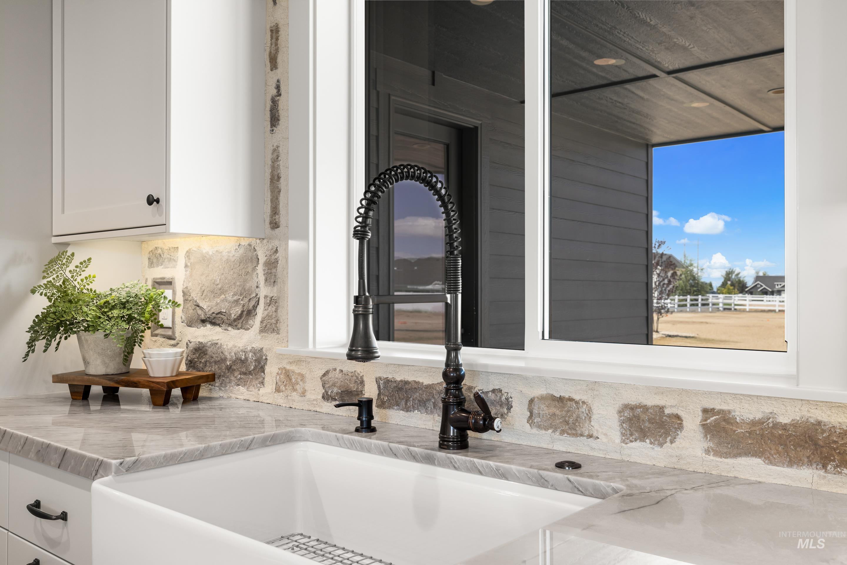 Kitchen view of decorative backsplash, light stone countertops, and white cabinetry