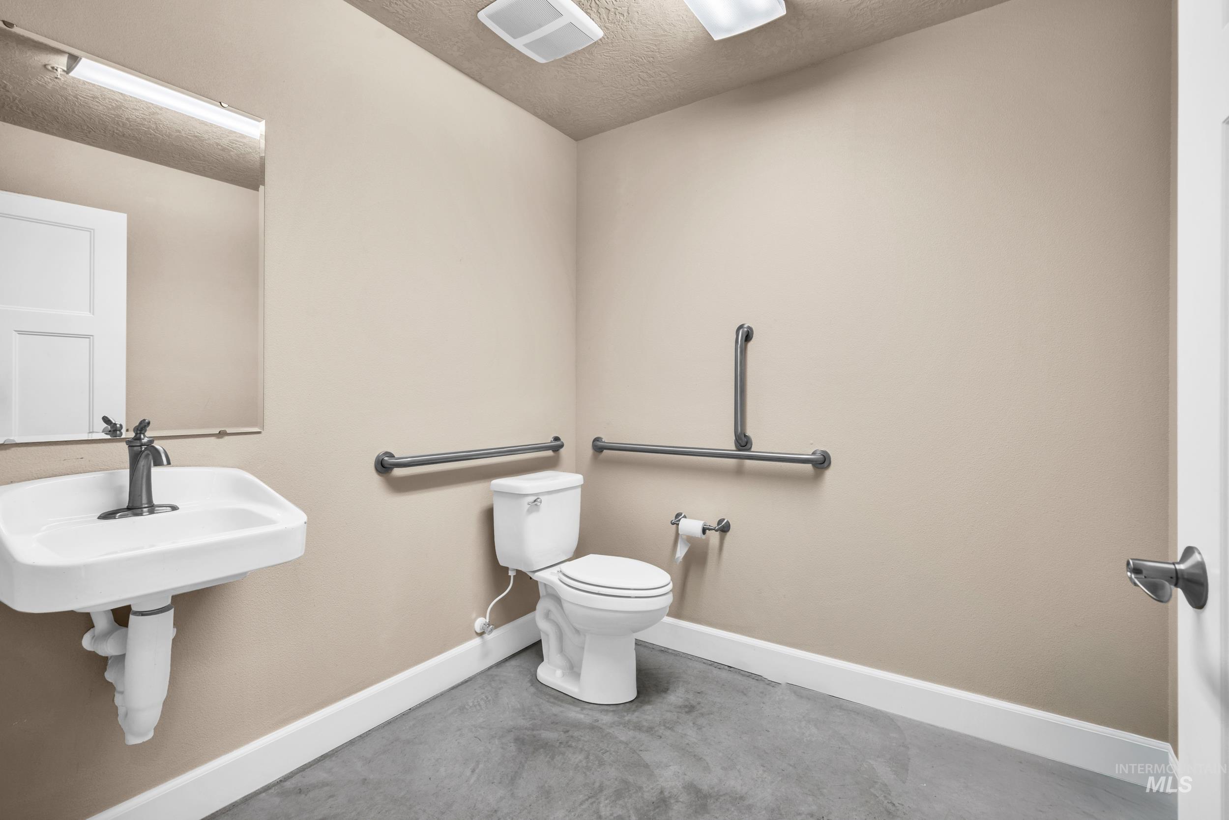 Bathroom with a textured ceiling and concrete floors
