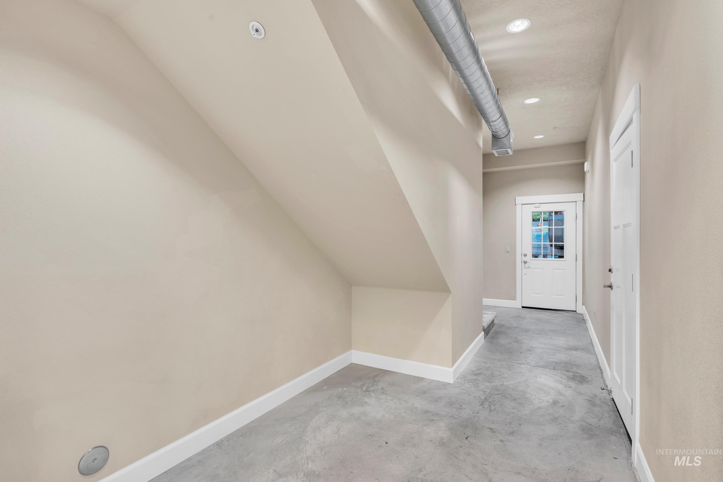 Corridor featuring unfinished concrete flooring and recessed lighting