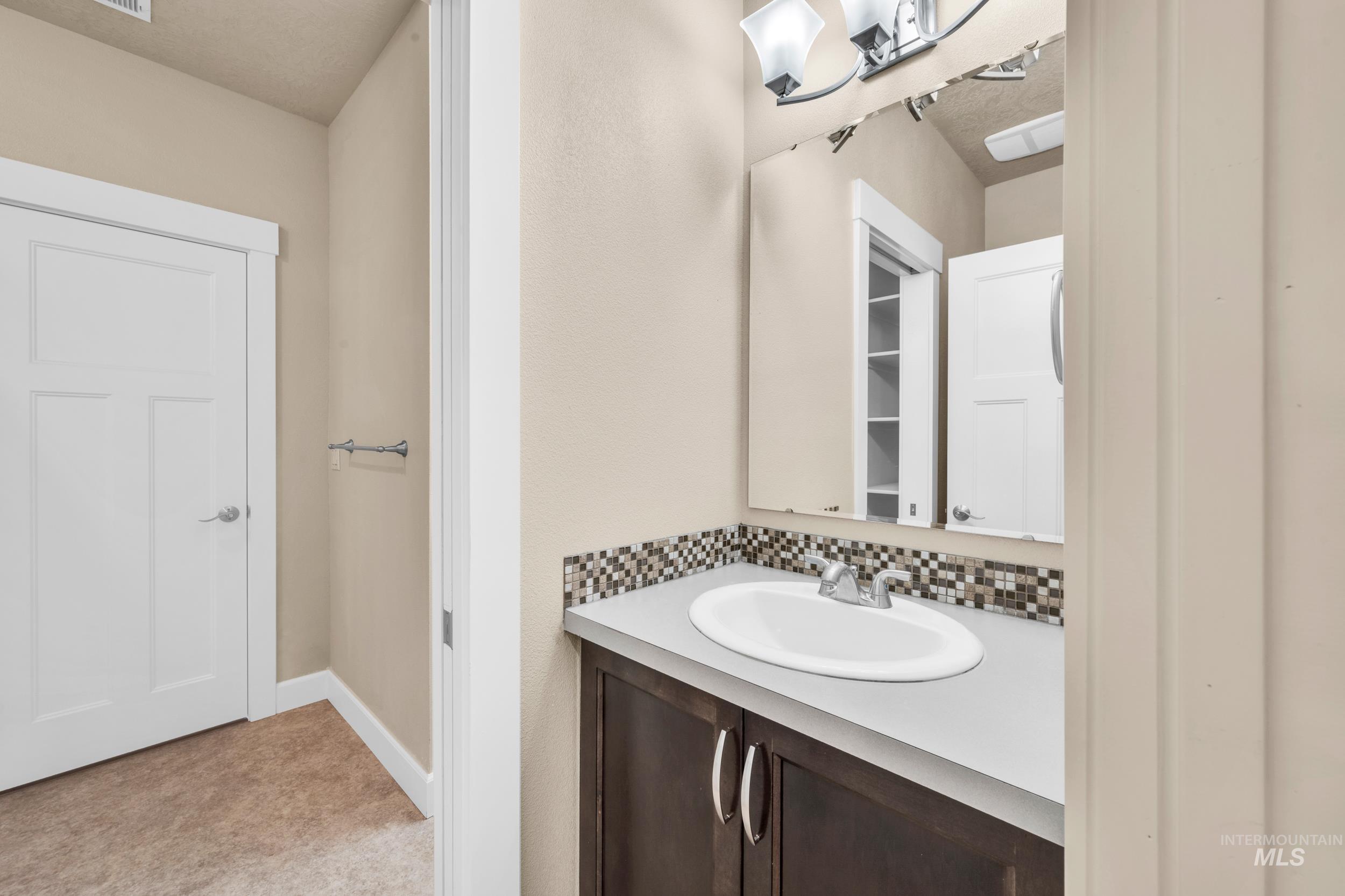 Bathroom featuring vanity and decorative backsplash