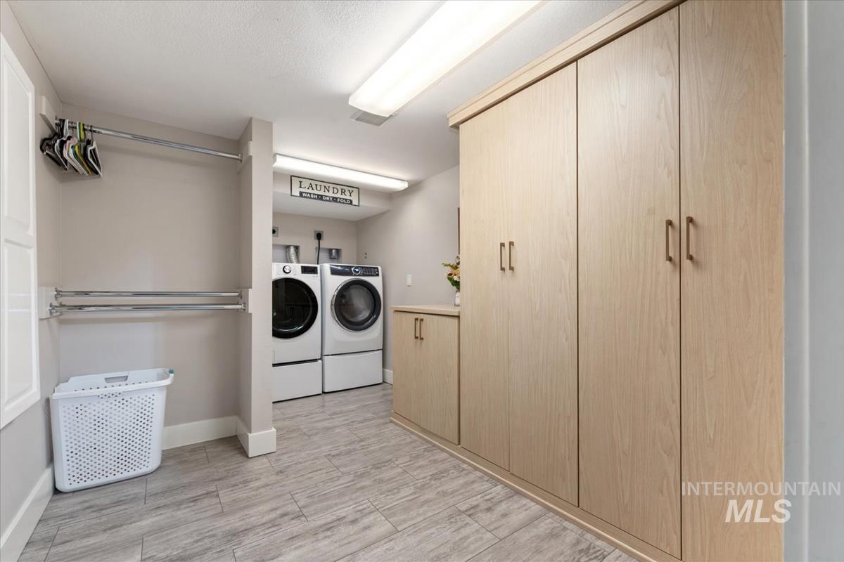 Washroom featuring cabinet space, washing machine and dryer, and wood tiled floors
