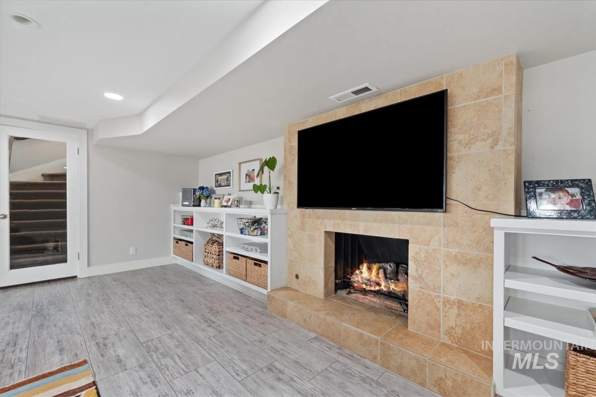 Unfurnished living room with a fireplace, wood finished floors, and stairs