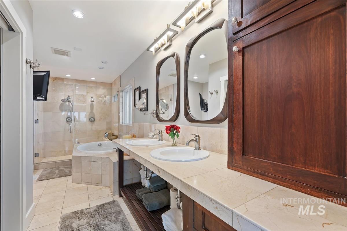 Full bathroom with a garden tub, double vanity, and a shower stall