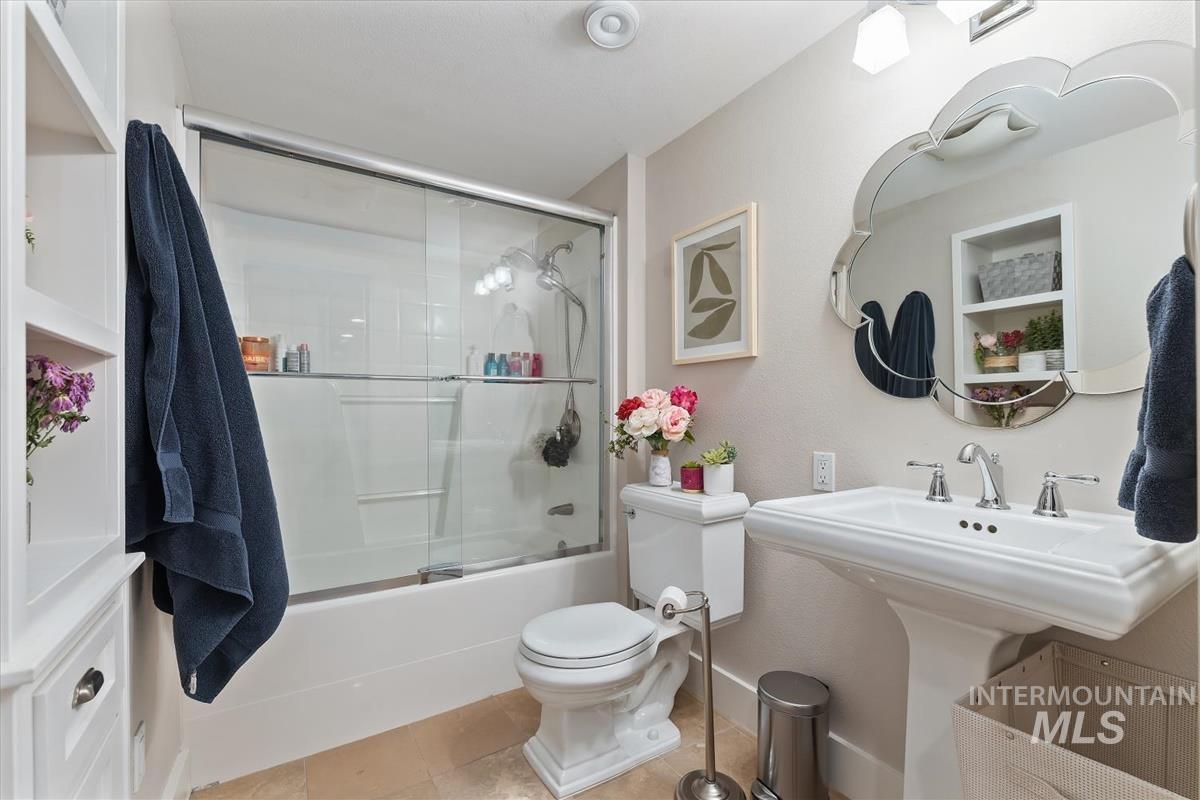Full bathroom with shower / bath combination with glass door and tile patterned flooring