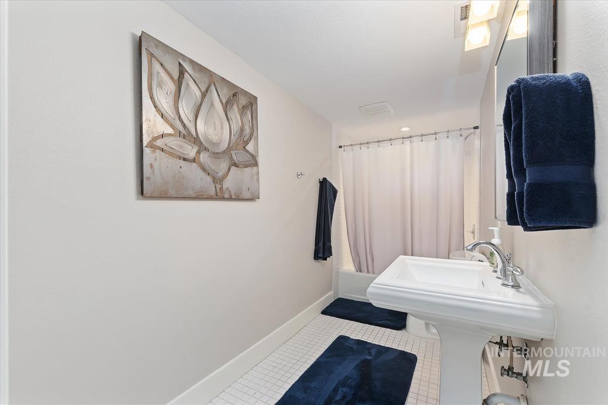 Full bath with shower / bath combination with curtain and tile patterned floors