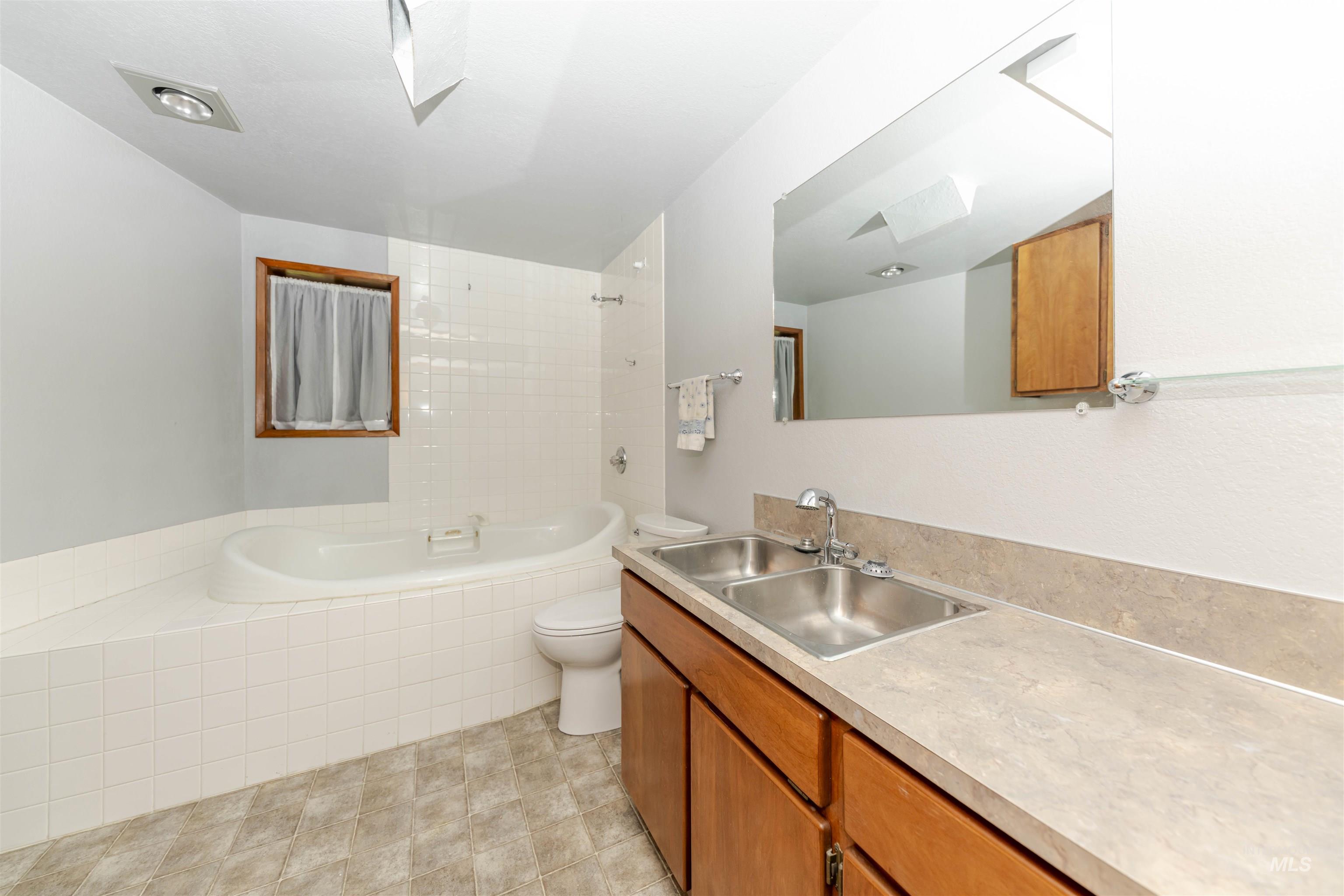 Full bath with jetted bathtub, toilet and vanity