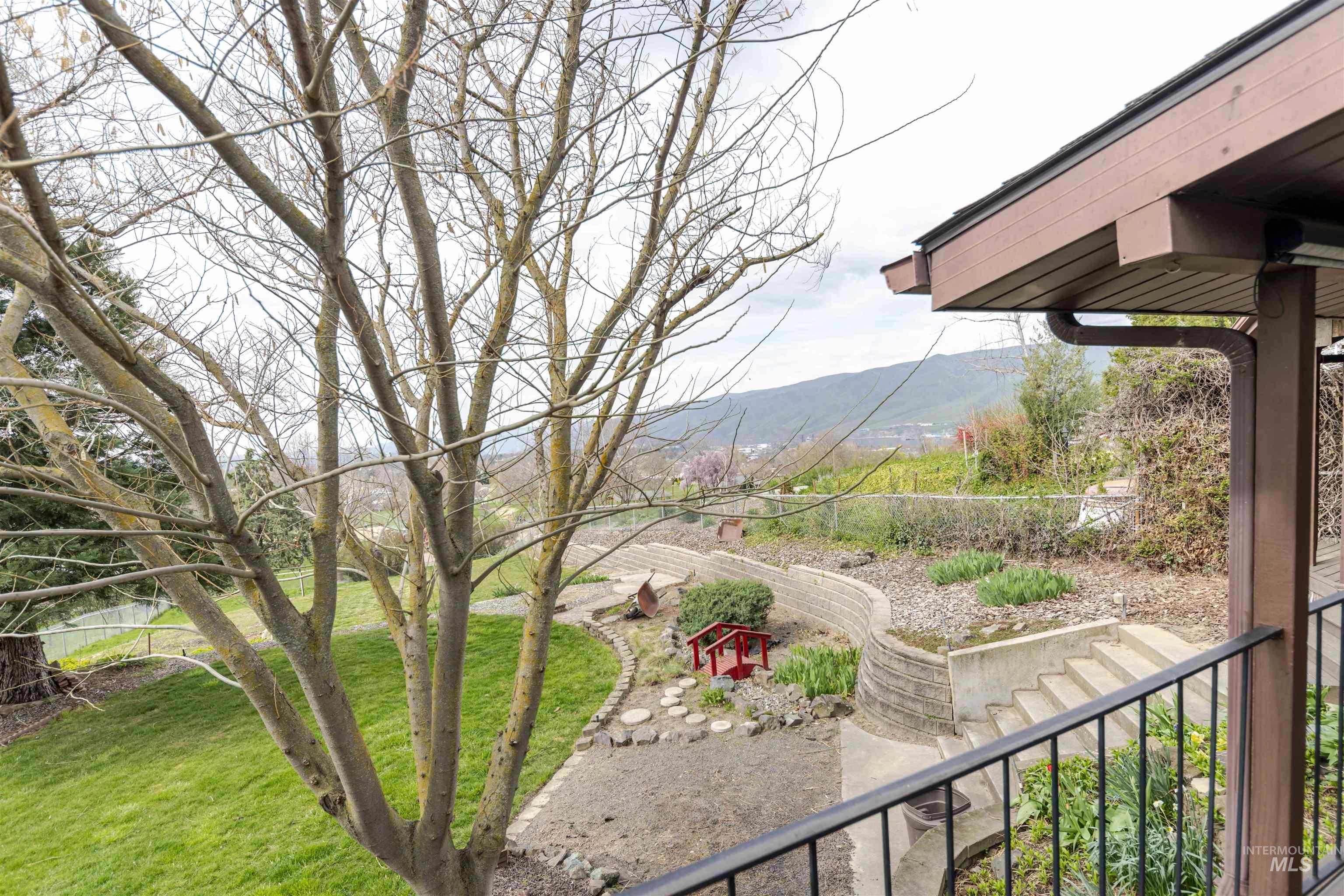 View of grassy yard with a mountain view and a balcony