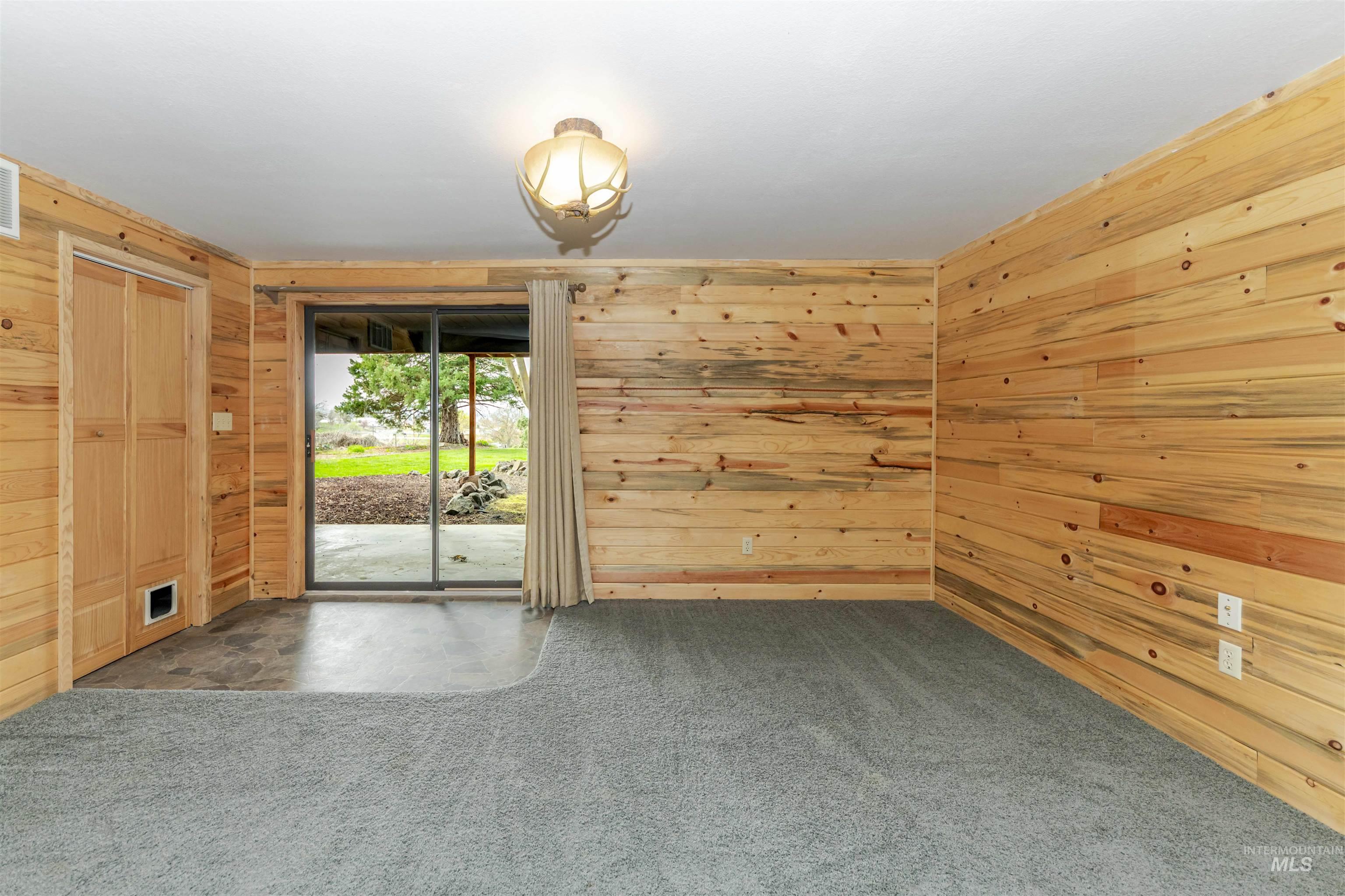 Carpeted family room with access to backyard featuring wooden walls