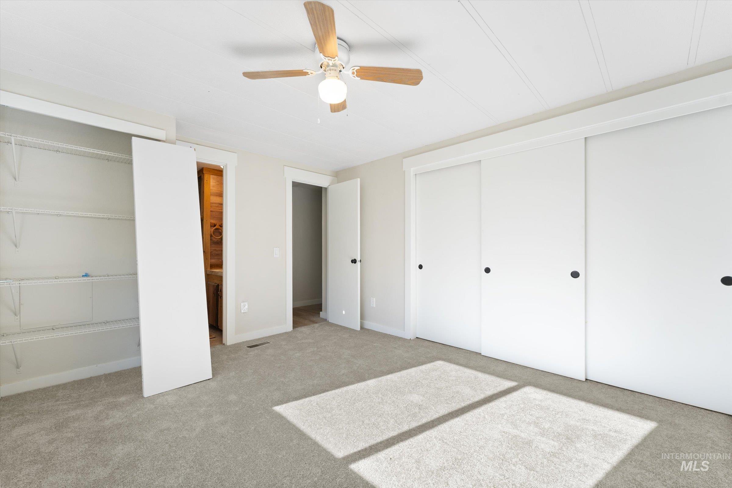 Unfurnished bedroom with multiple closets, carpet flooring, and ceiling fan