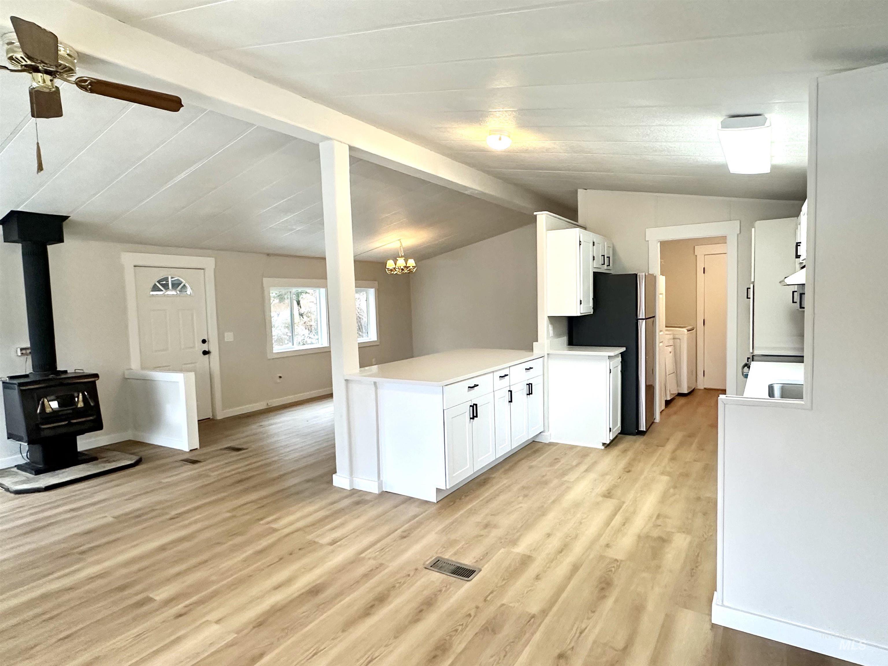 Kitchen with white cabinets, light countertops, a wood stove, open floor plan, and a peninsula