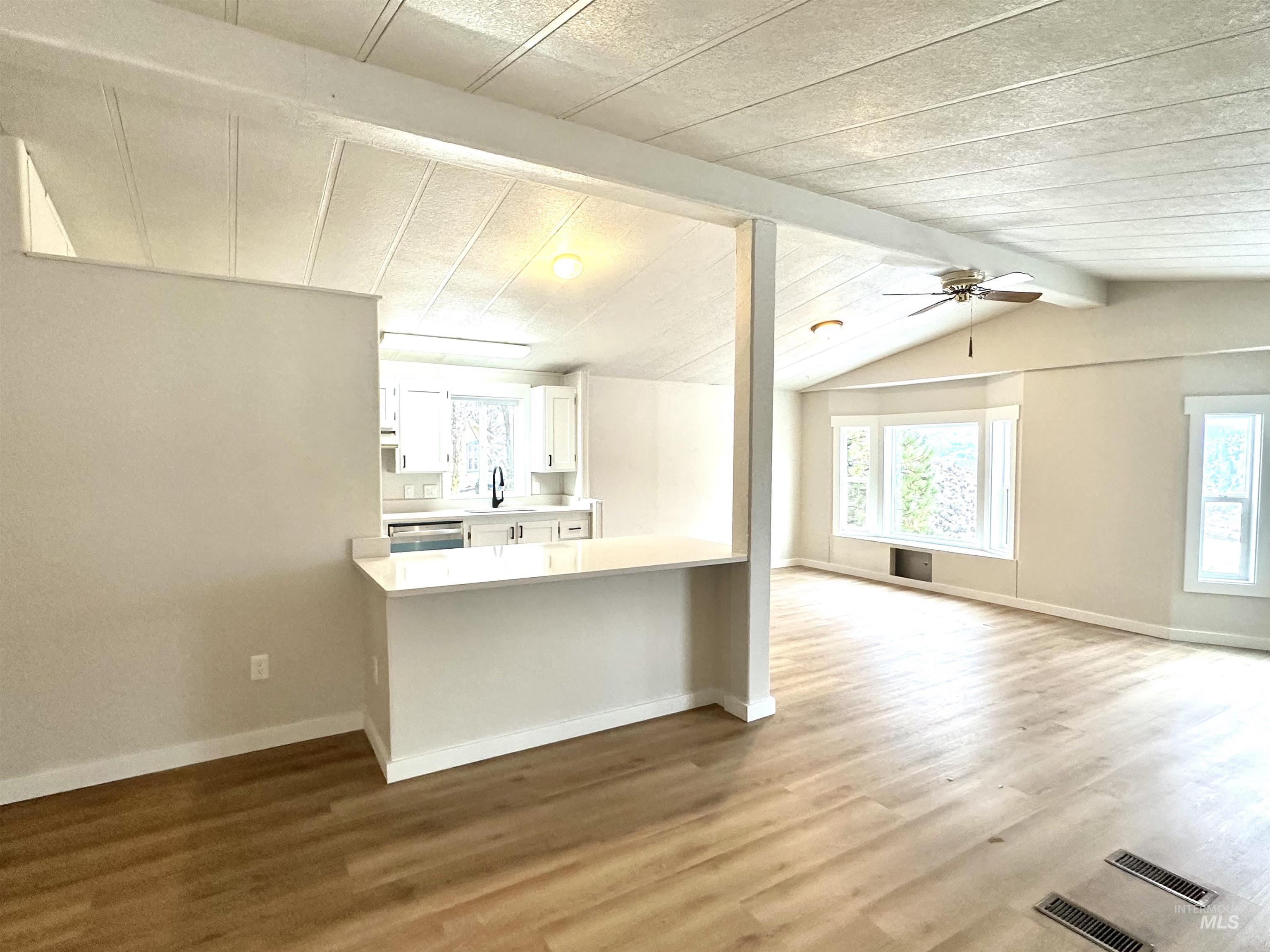 Kitchen with light countertops, white cabinets, dark wood-style floors, a peninsula, and ceiling fan