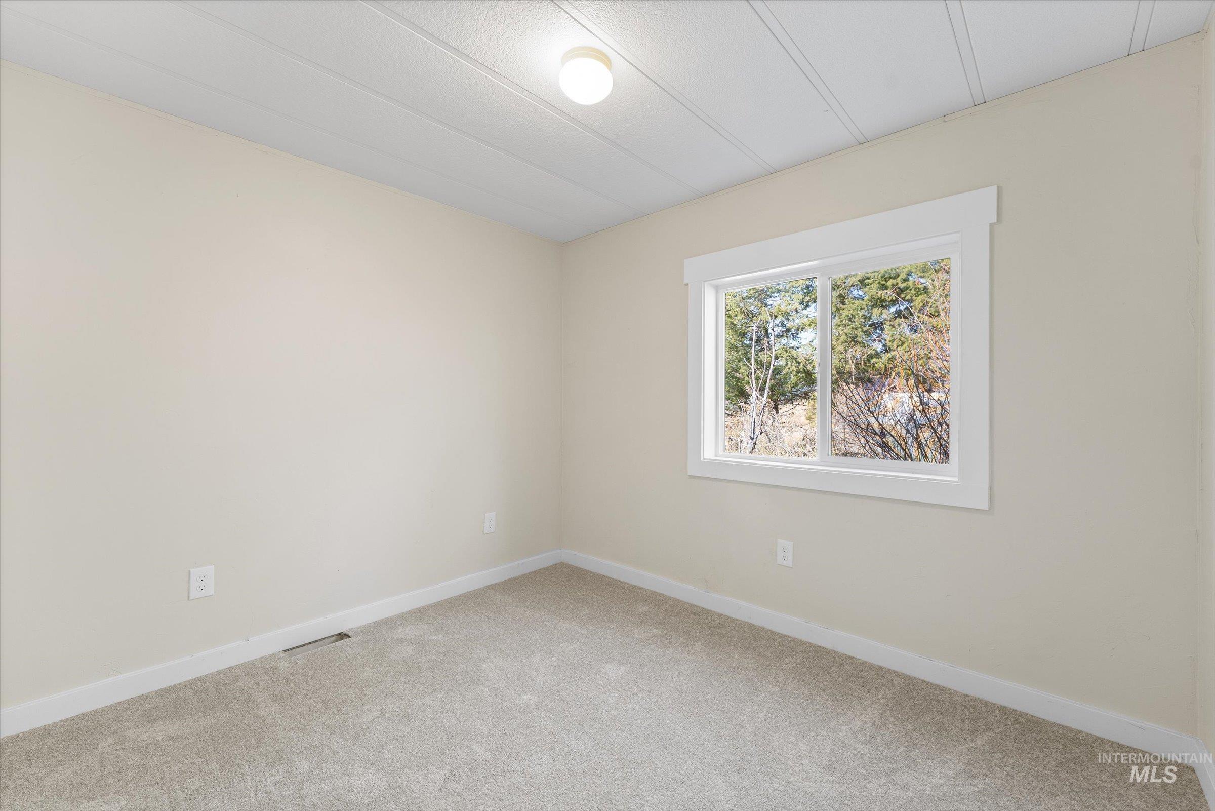 Carpeted empty room featuring baseboards