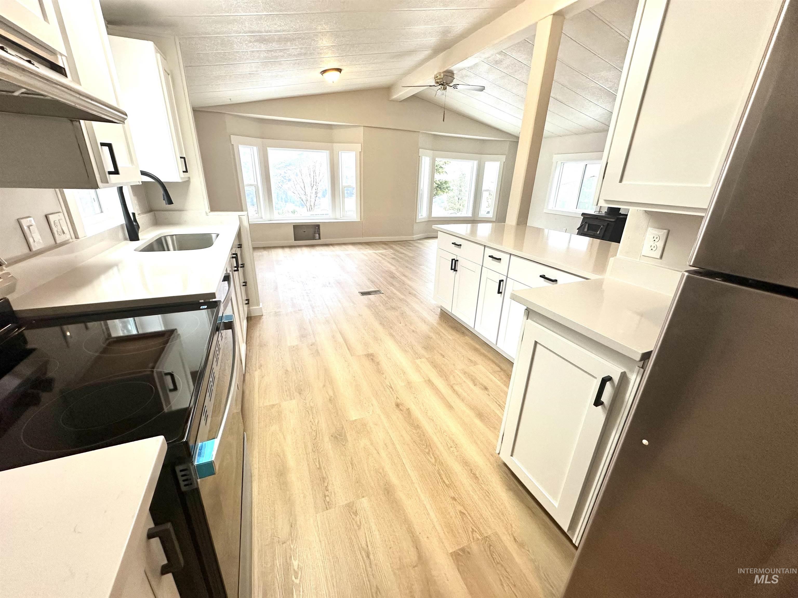 Kitchen featuring white cabinets, light wood-style flooring, electric range, ventilation hood, and open floor plan