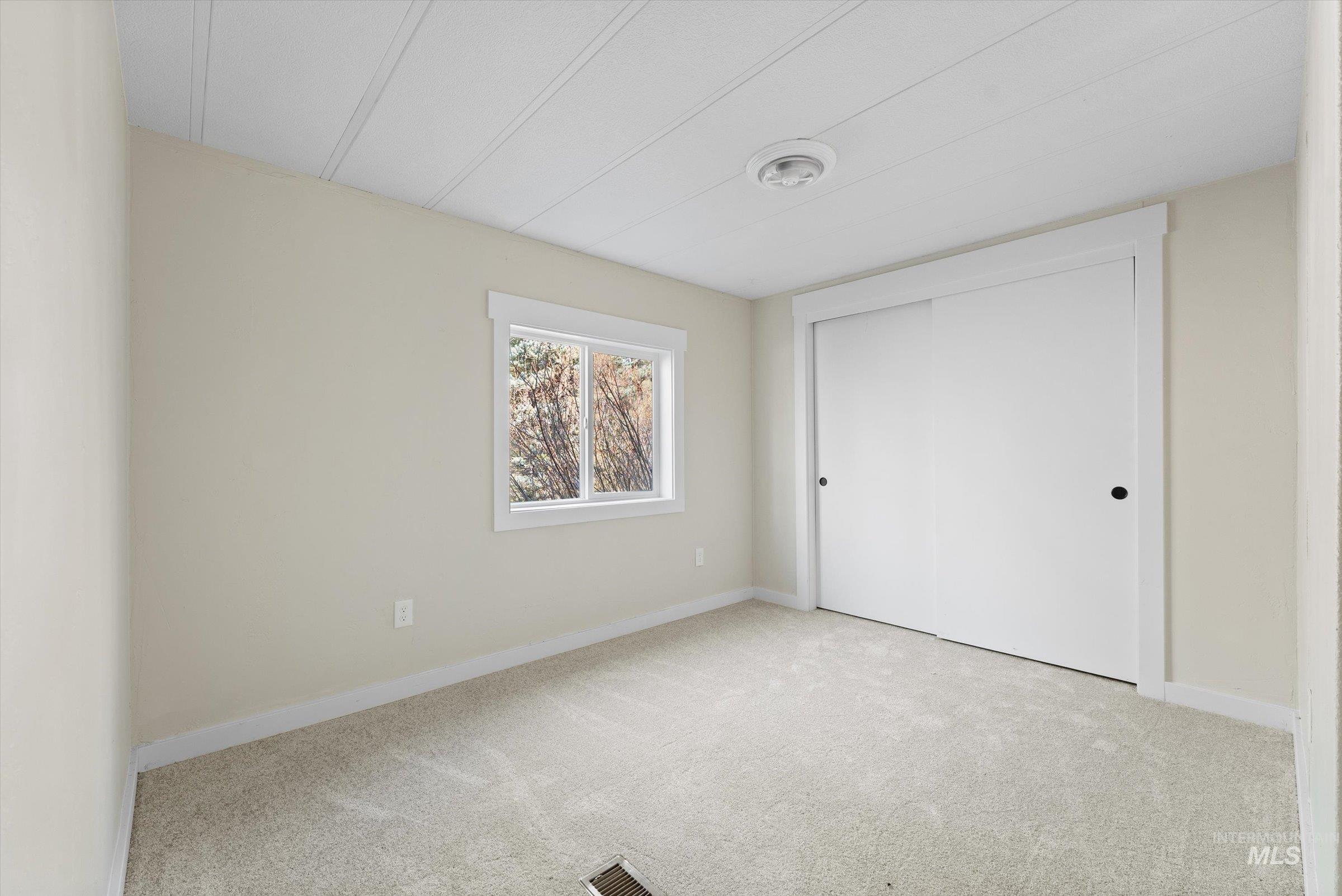 Unfurnished bedroom with light carpet and a closet