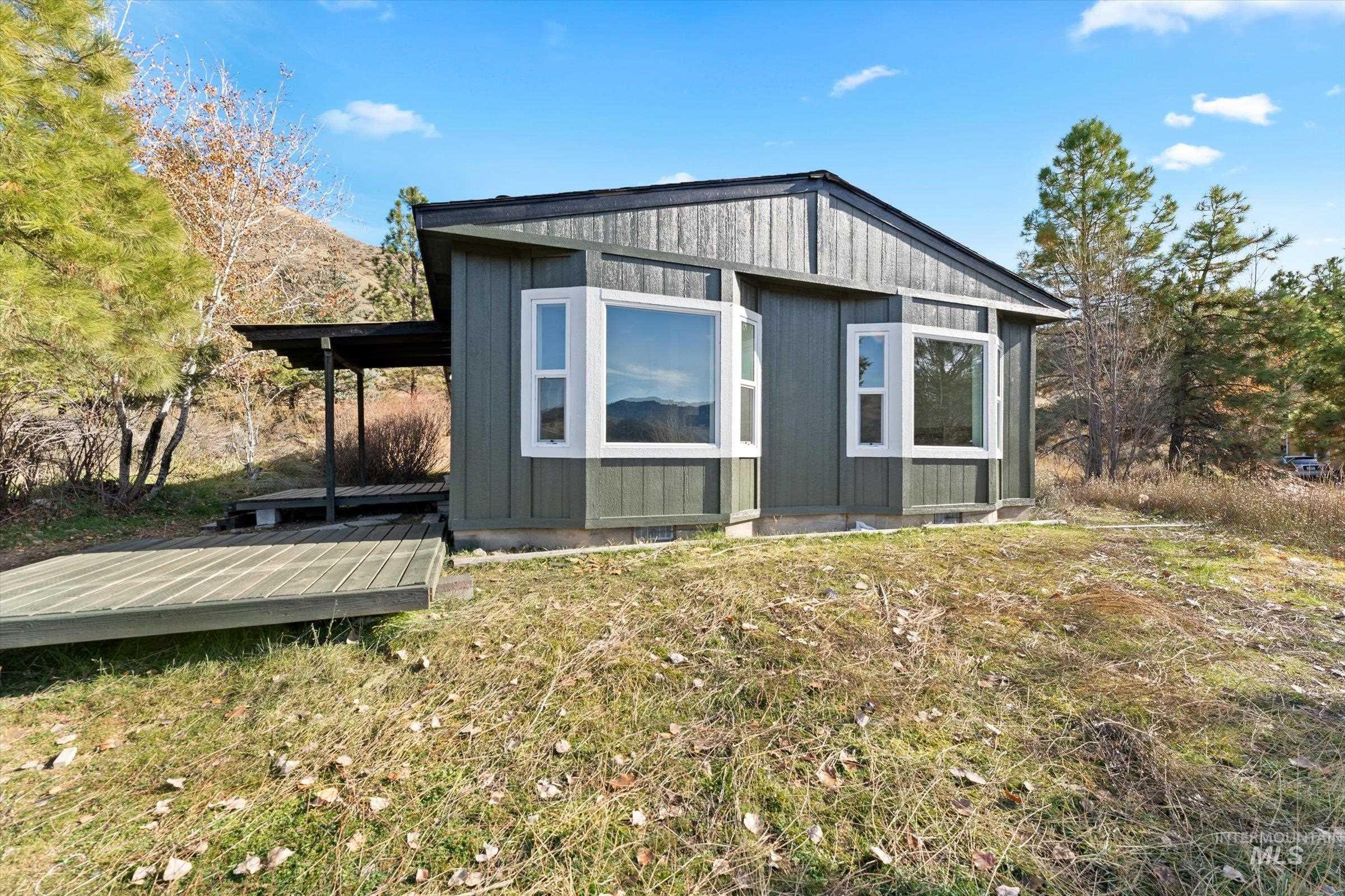View of side of property with a deck, an outdoor structure, and a lawn
