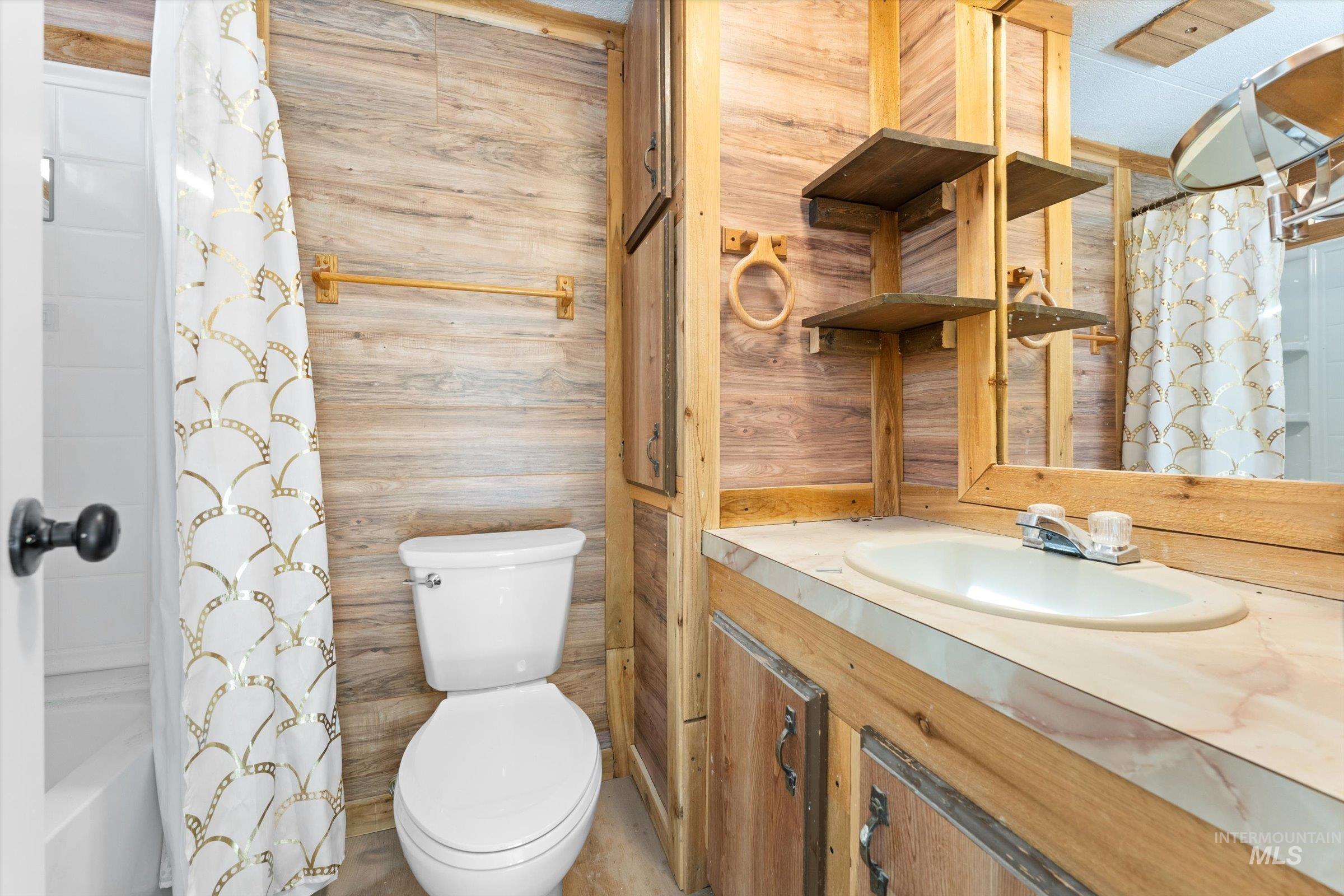 Bathroom with vanity, shower / bath combination with curtain, and wooden walls