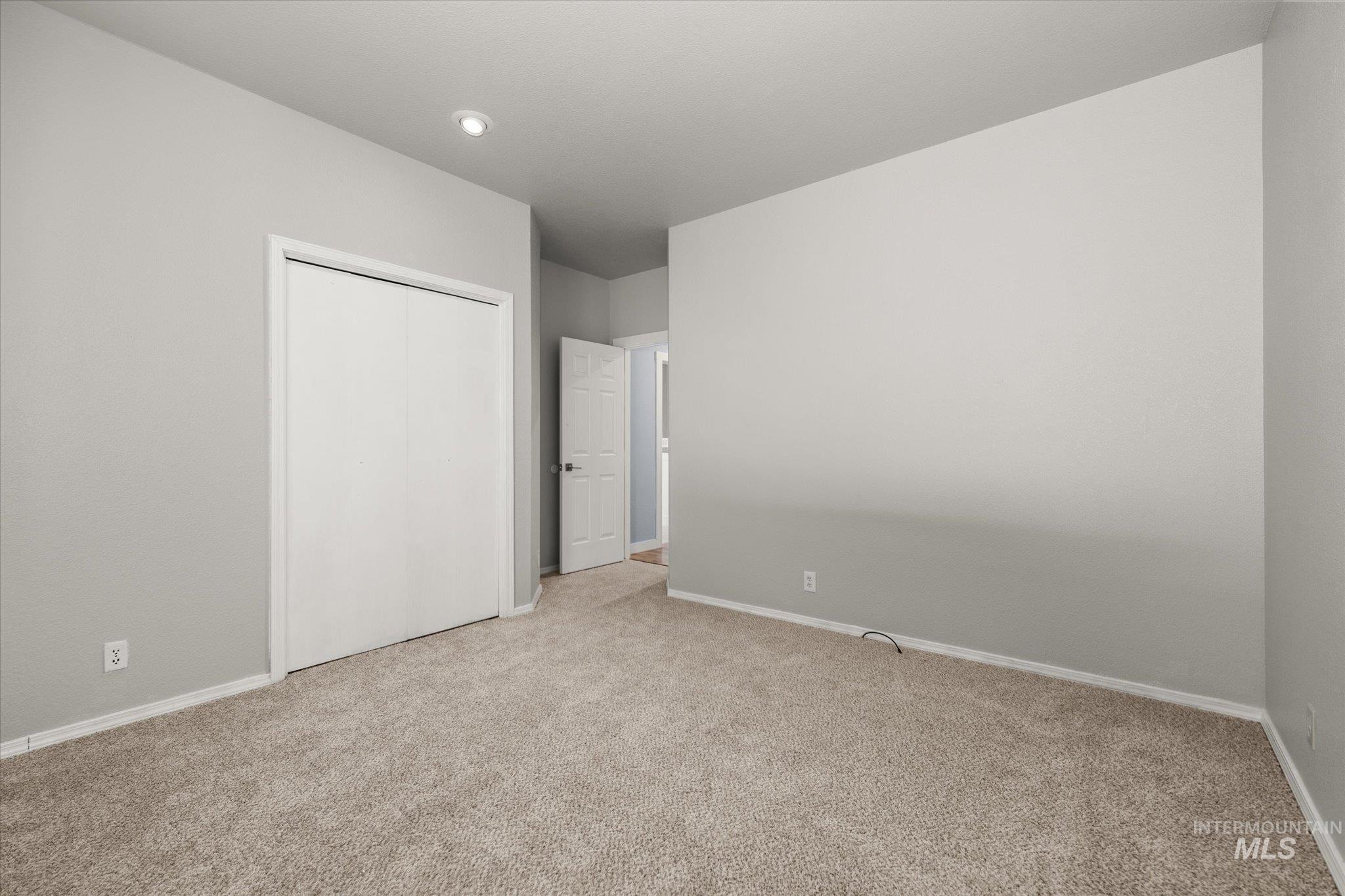 Unfurnished bedroom with light colored carpet and a closet