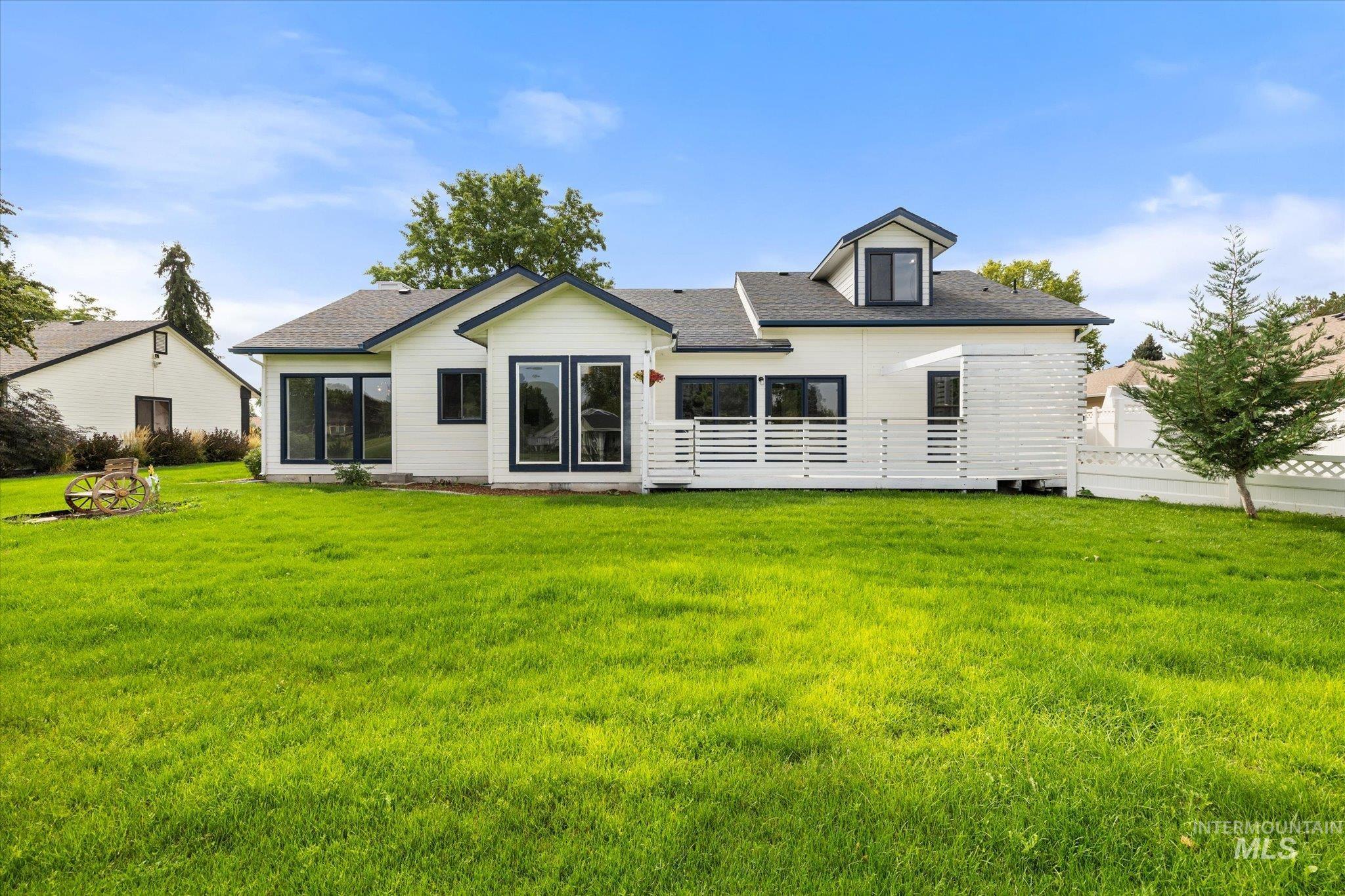 Back of property with roof with shingles and a yard