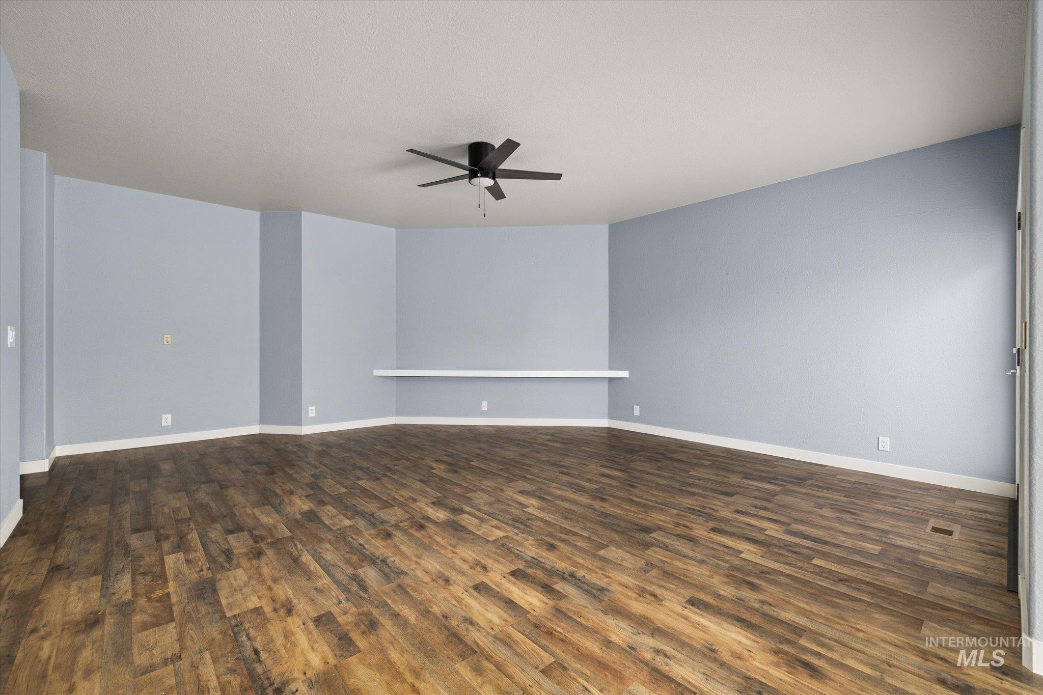 Spare room featuring dark wood finished floors and ceiling fan