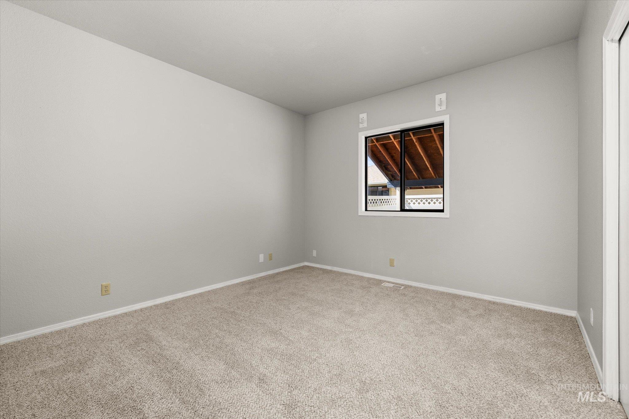 Unfurnished room featuring light carpet and baseboards