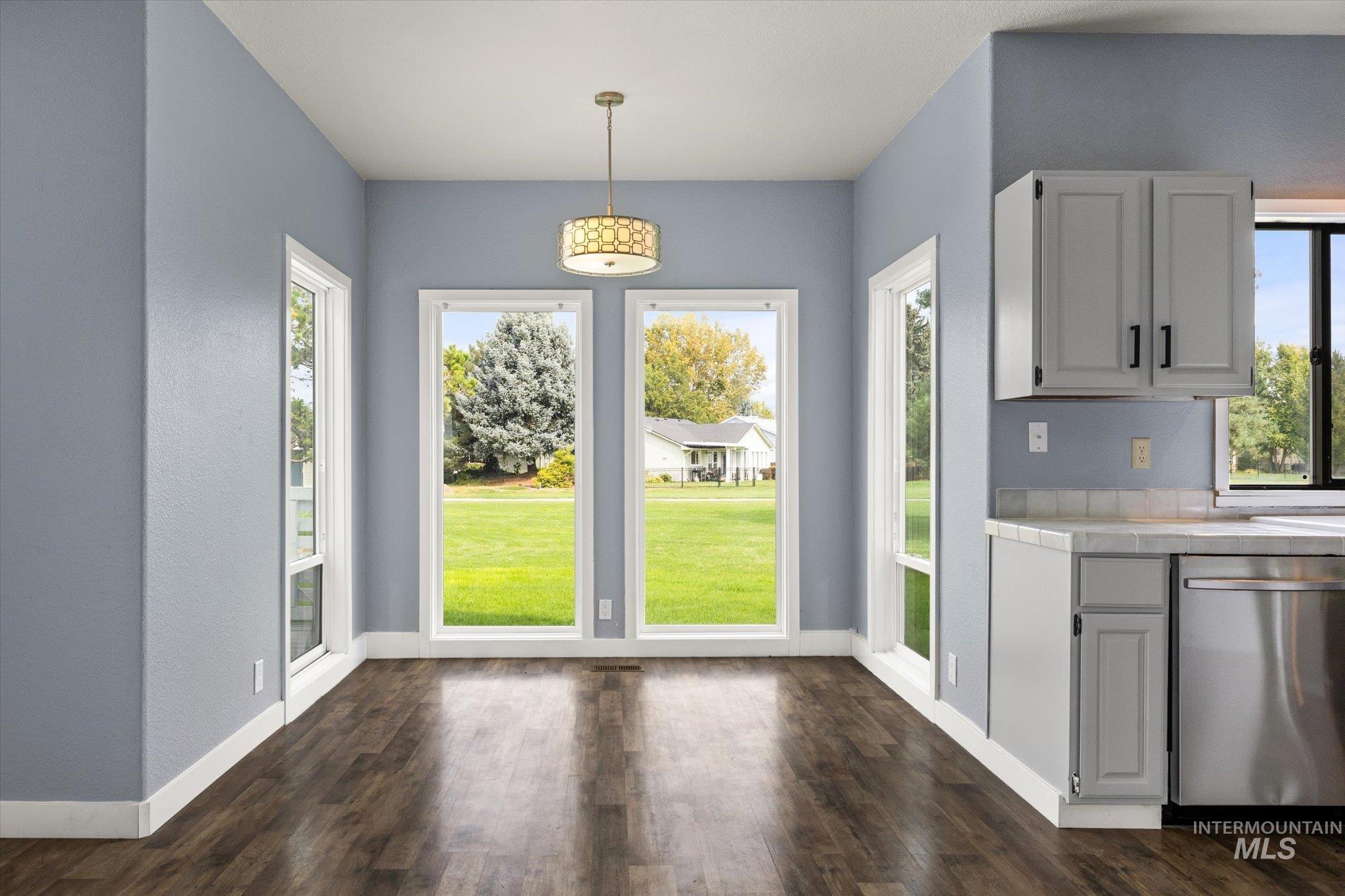 Unfurnished dining area with dark wood finished floors and baseboards
