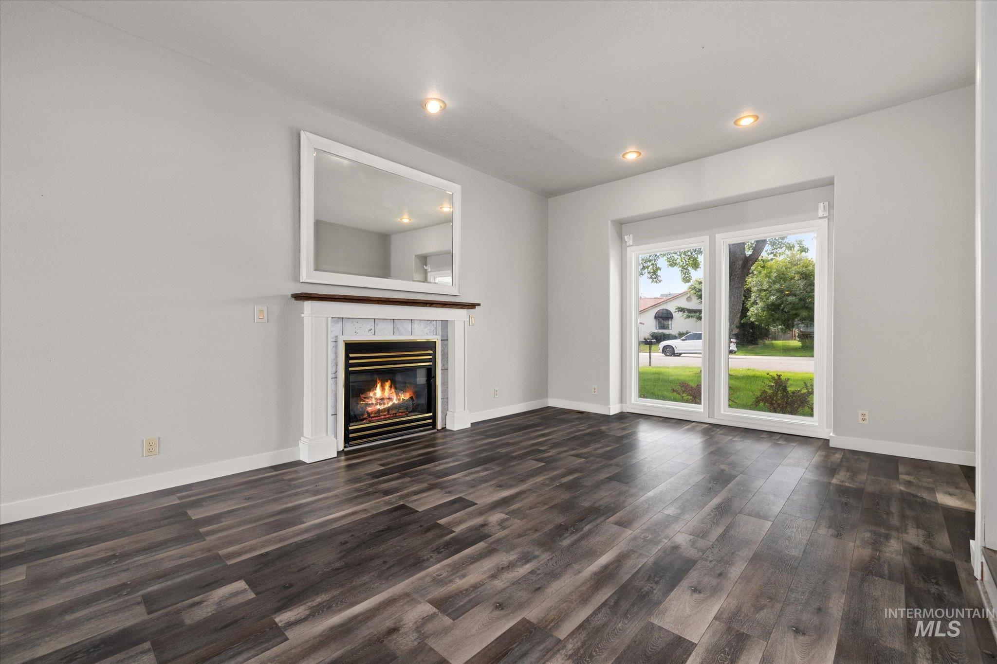 Unfurnished living room with dark wood-style flooring, a tile fireplace, and recessed lighting