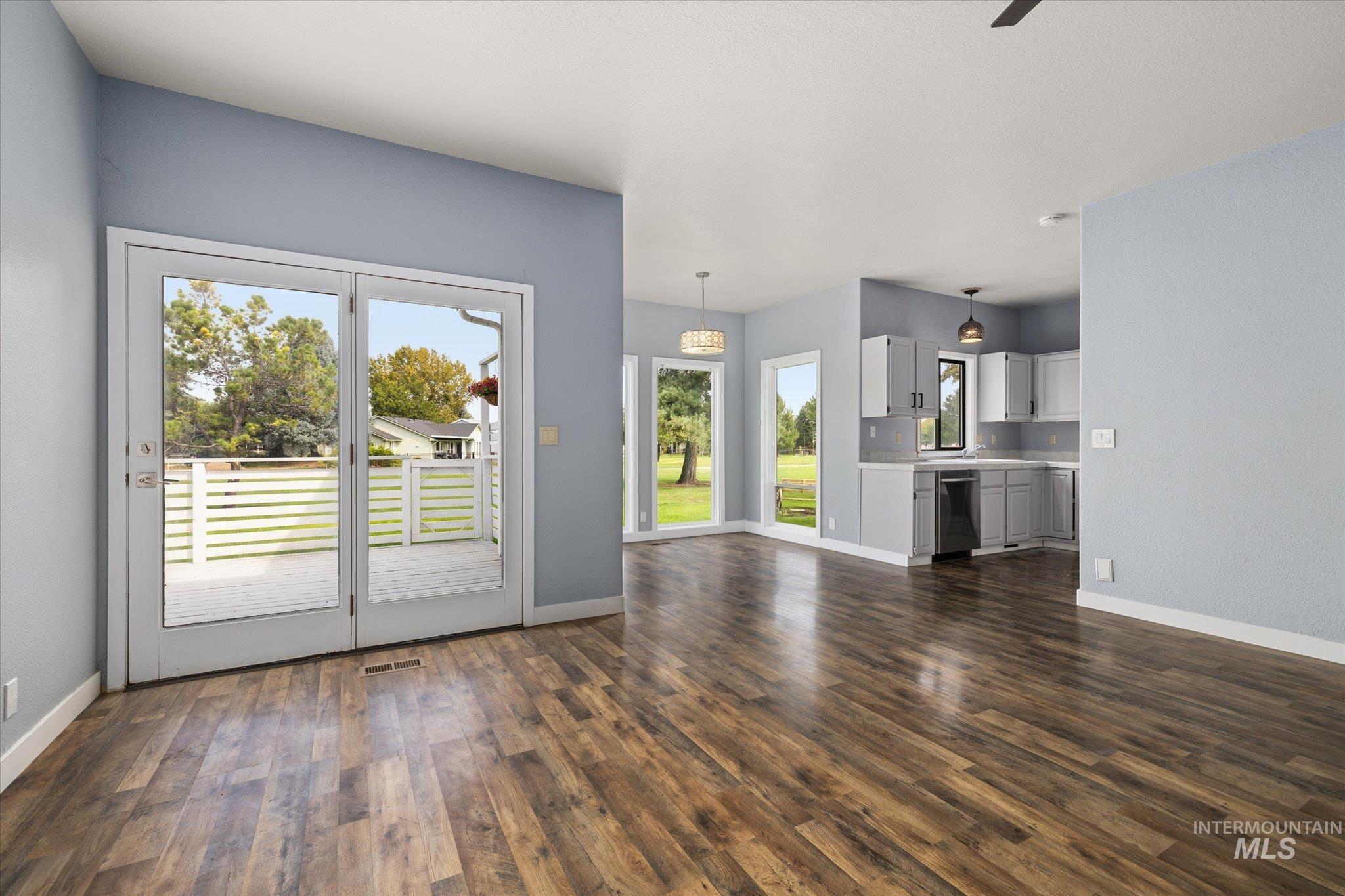 Unfurnished living room featuring dark wood-style floors and a ceiling fan