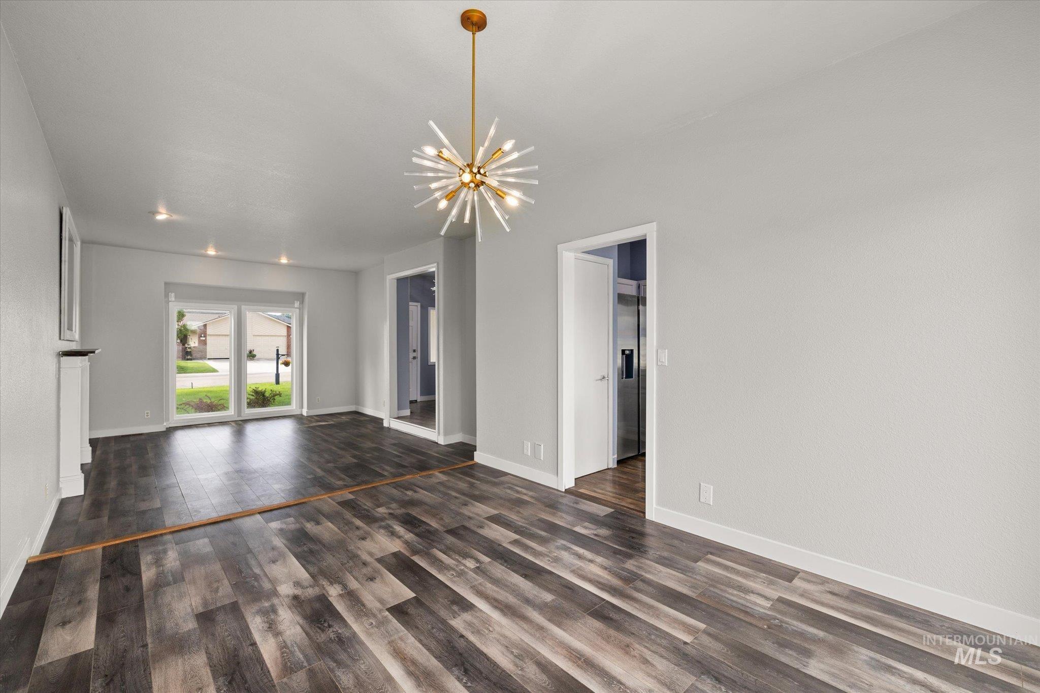 Unfurnished living room featuring a chandelier and dark wood finished floors