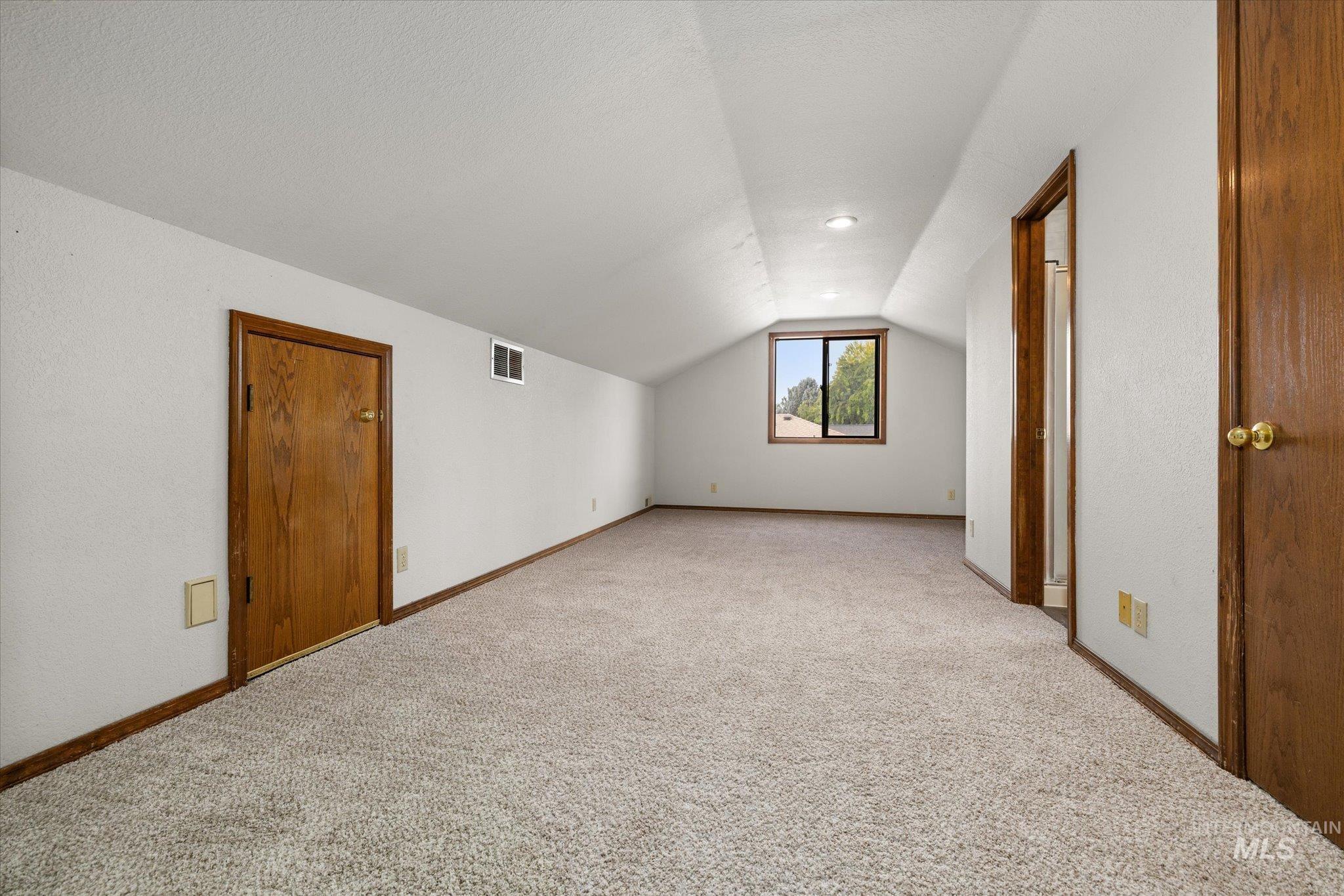 Additional living space with vaulted ceiling, carpet floors, and a textured ceiling
