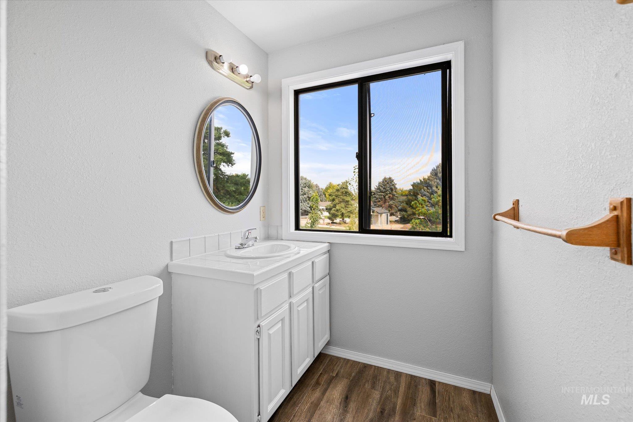 Half bathroom featuring dark wood-type flooring, a textured wall, and vanity
