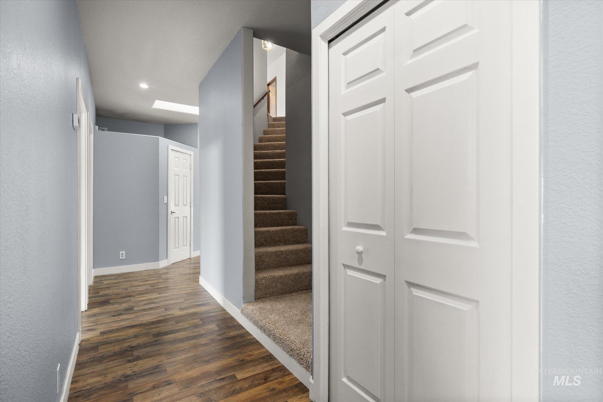 Corridor with dark wood-style floors, stairs, recessed lighting, and a textured wall