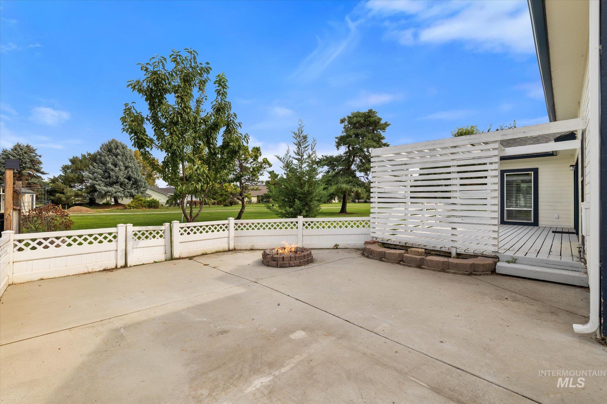 View of patio with an outdoor fire pit and a deck
