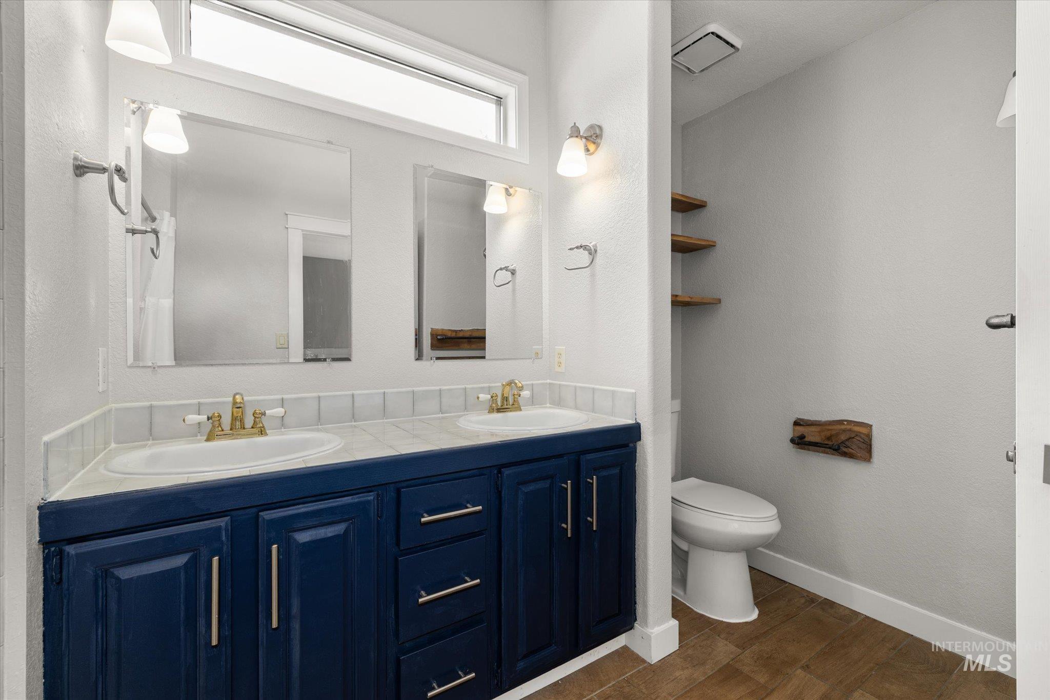 Bathroom with double vanity and dark wood-style flooring