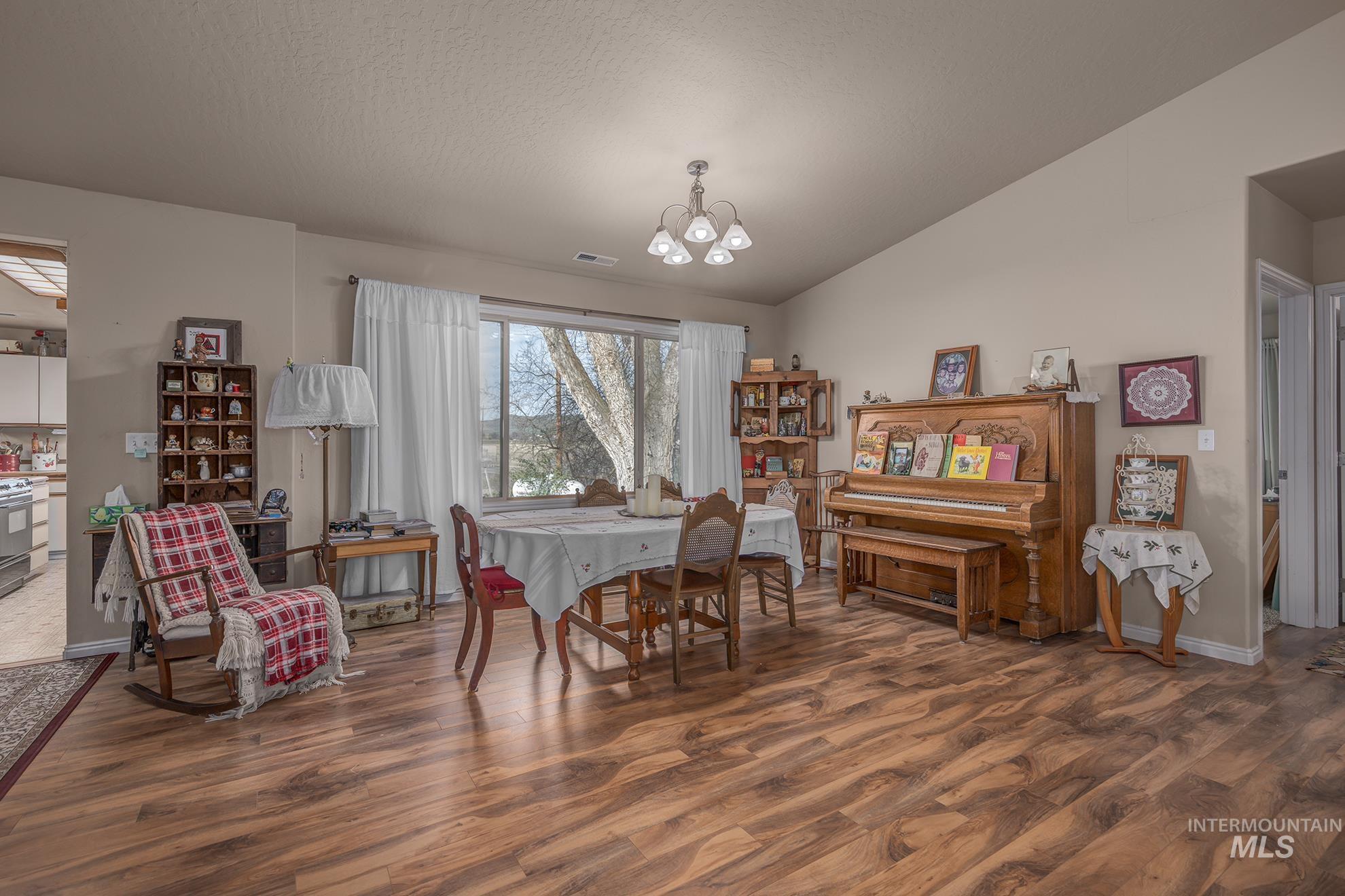 Dining room with dark wood-type flooring, lofted ceiling, and a chandelier