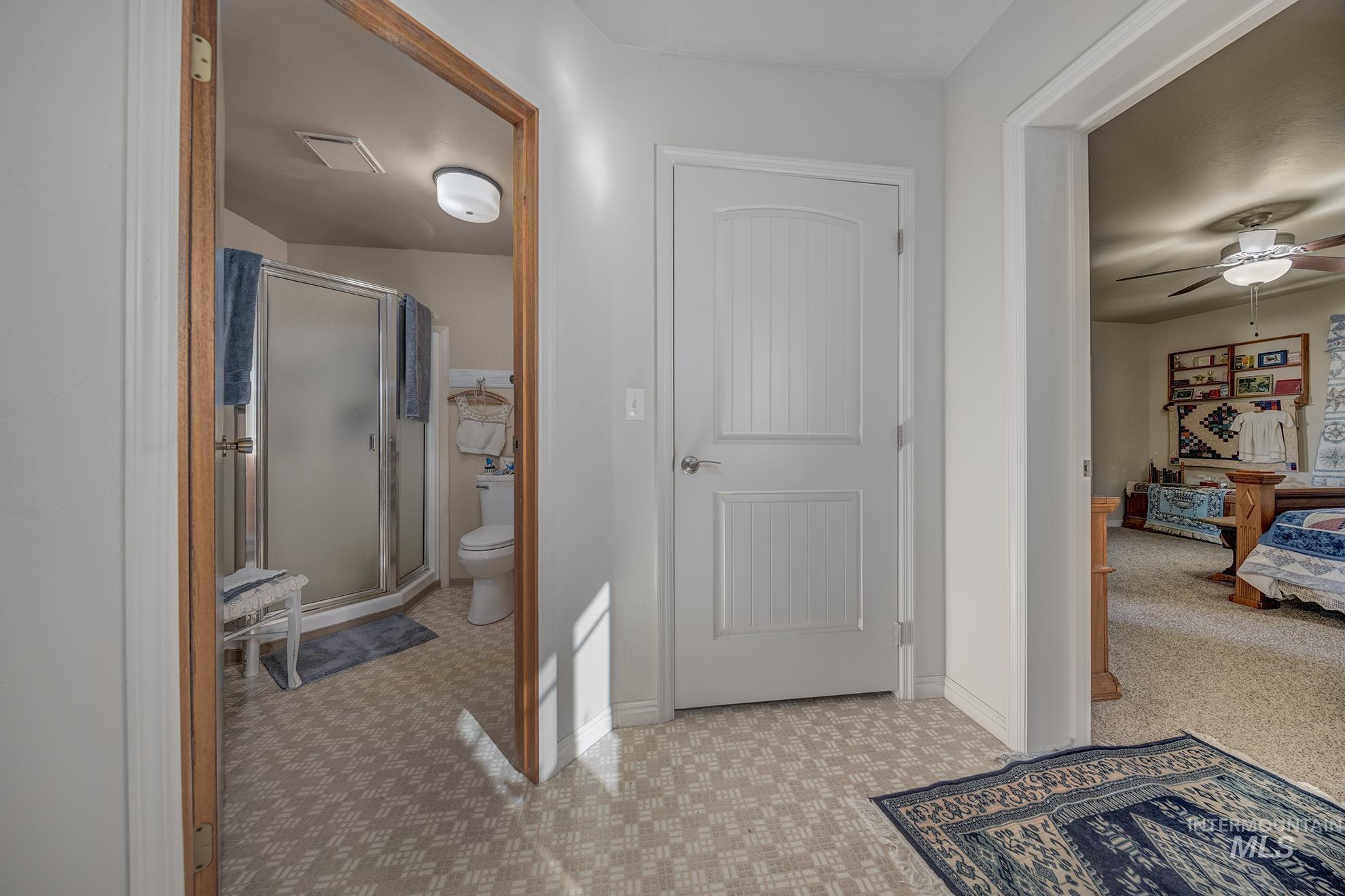 Full bathroom with connected bathroom, a shower stall, light carpet, and a ceiling fan
