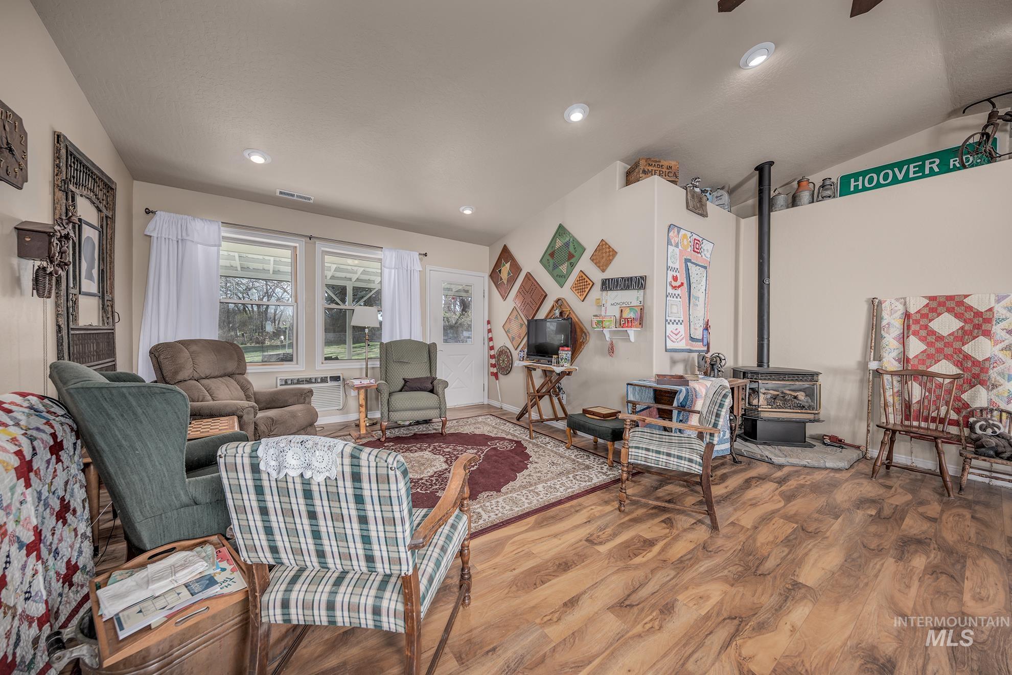 Living area featuring a wood stove, wood finished floors, ceiling fan, lofted ceiling, and recessed lighting