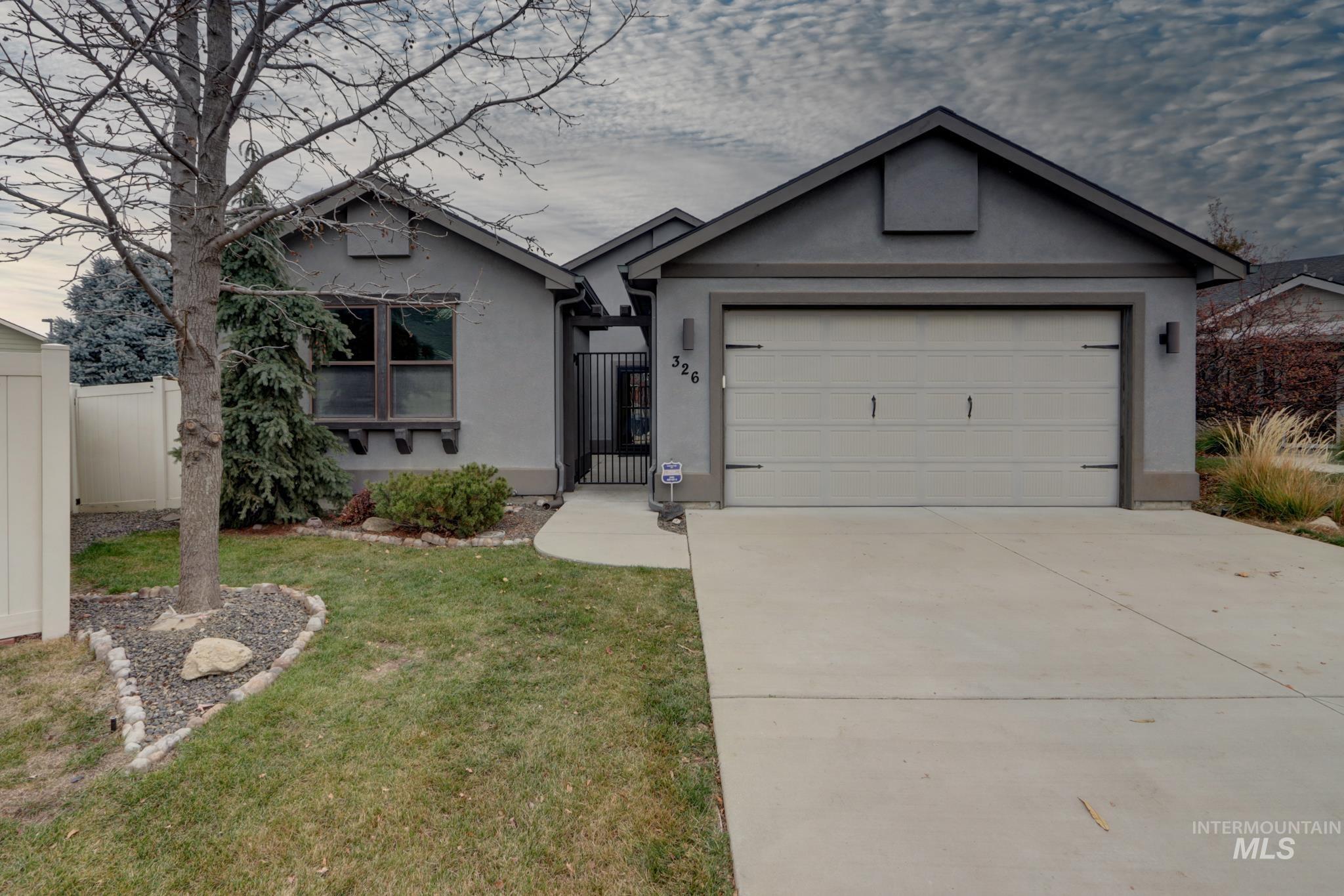 Ranch-style house featuring stucco siding, driveway, a garage, and a gate