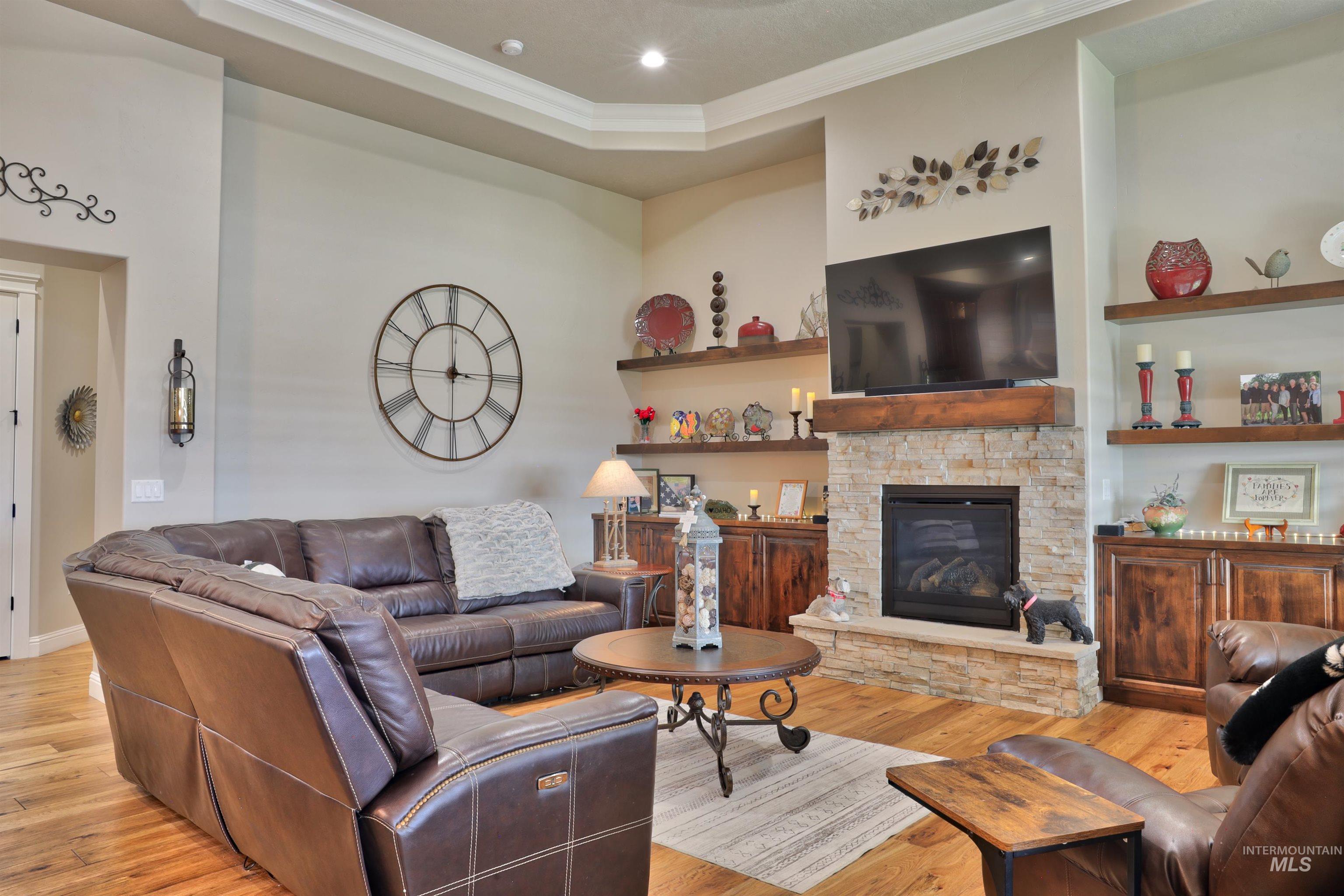 Living room featuring light wood-type flooring, a fireplace, ornamental molding, and recessed lighting