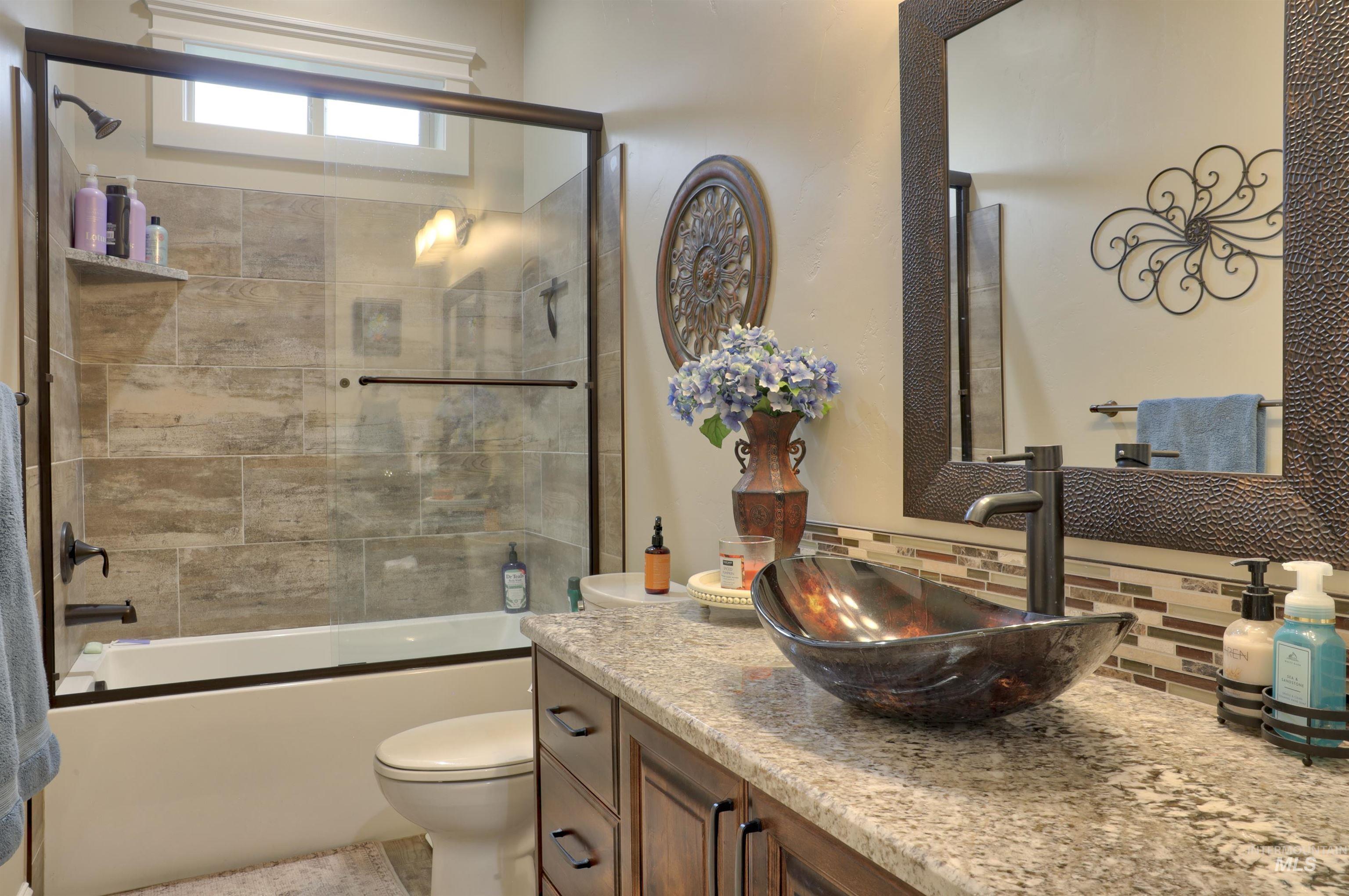 Full bathroom with vanity, bath / shower combo with glass door, and backsplash