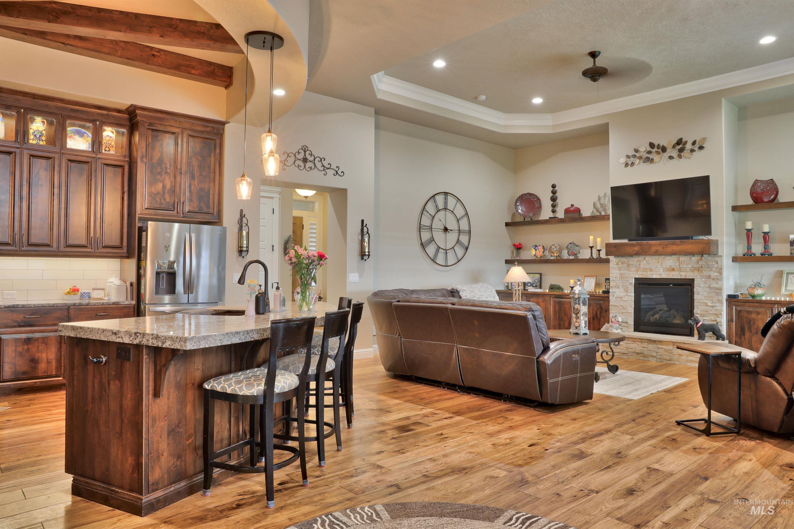 Kitchen with a kitchen breakfast bar, open floor plan, stainless steel fridge, a center island with sink, and glass insert cabinets