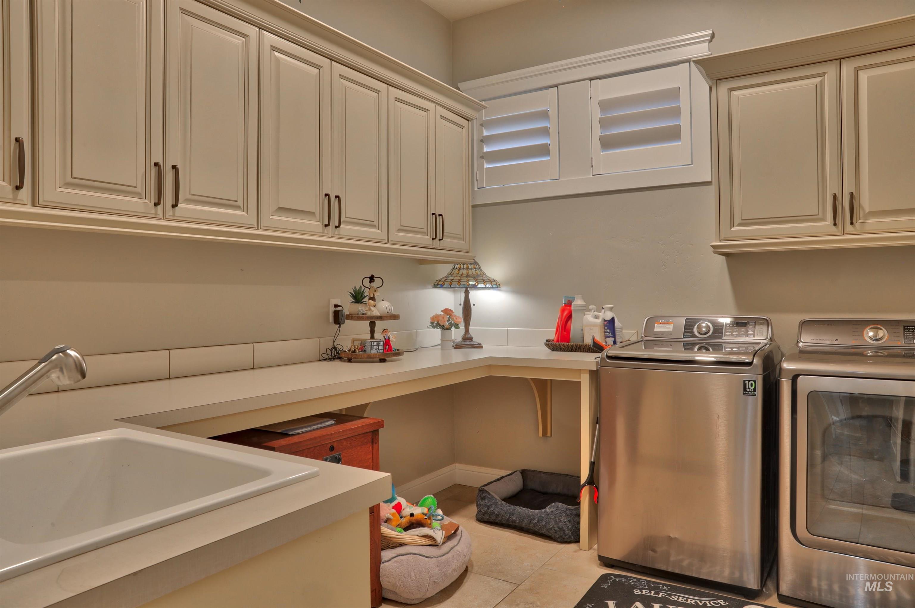 Laundry area with washer and clothes dryer, light tile patterned floors, and cabinet space